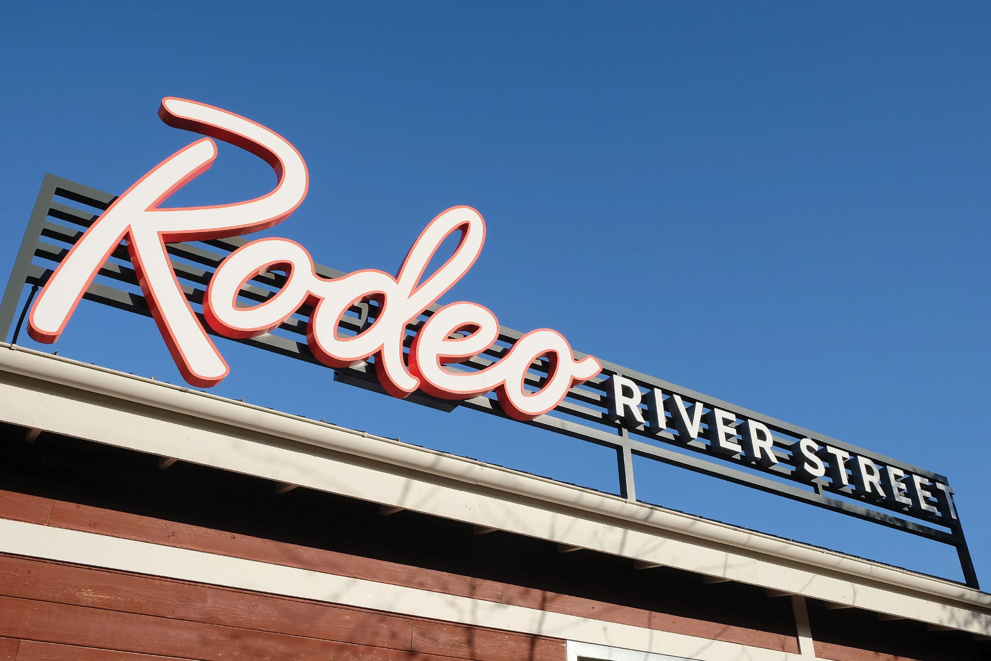 River Street Marketplace Rodeo River Street rooftop signage against blue sky, environmental graphic design by RSM Design