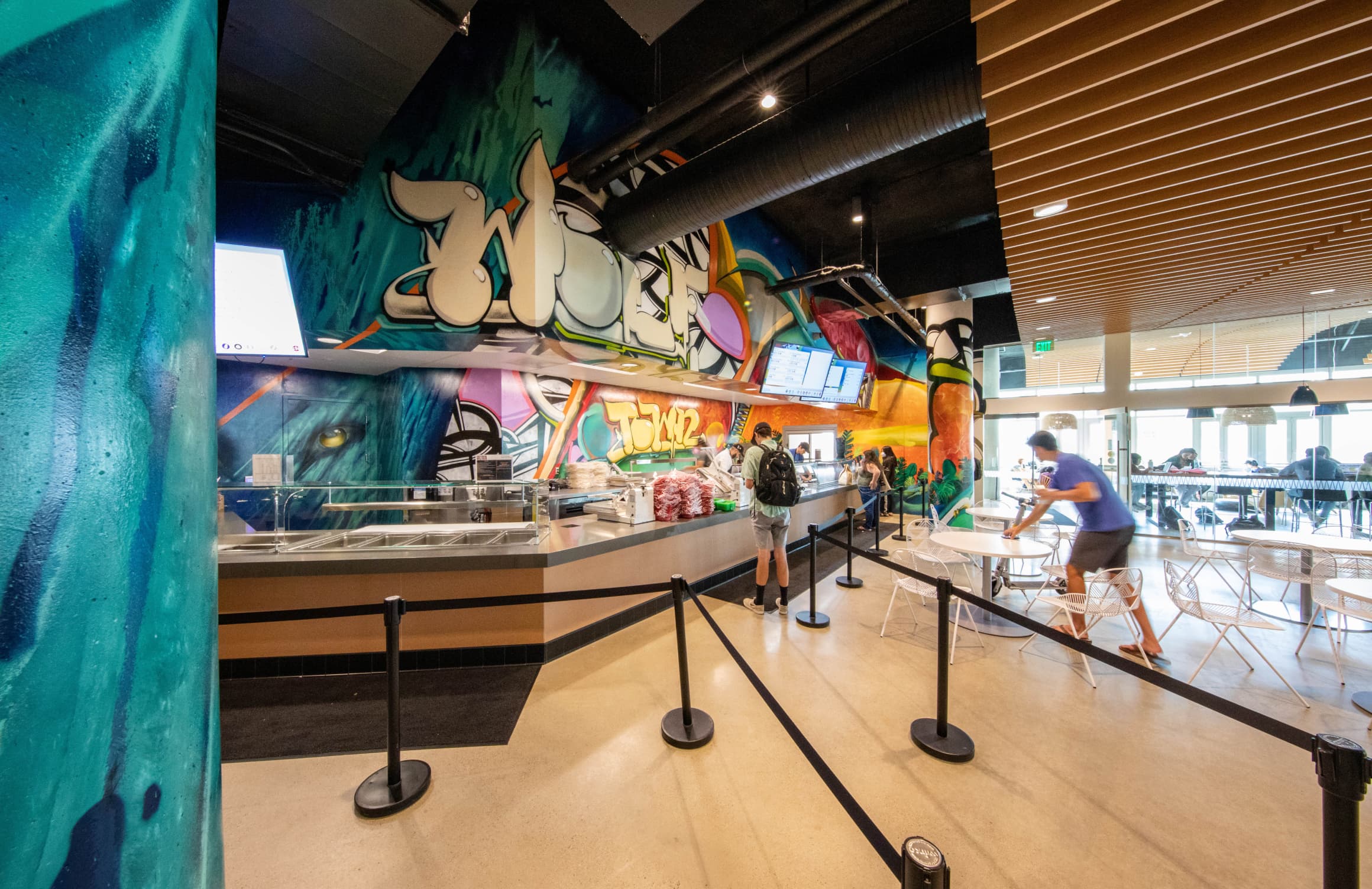 Storefront of Wolftown with painted mural by Max Moses with bold colors and graphics for UC San Diego Sixth College's dining hall by RSM Design in San Diego, California. 
