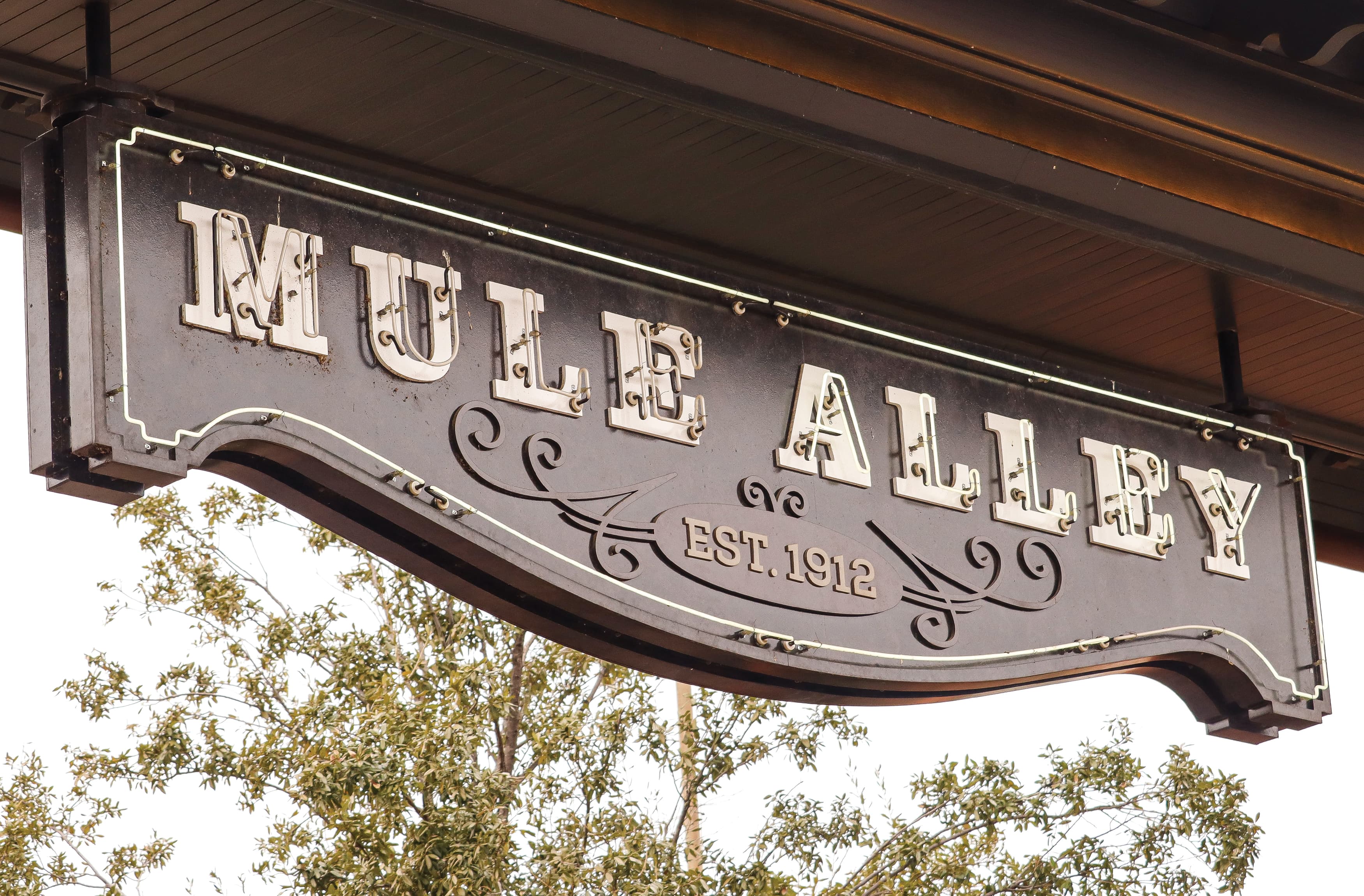 "Mule Alley" sign with est. 912 include at the Fort Worth Stockyards in Fort Worth, Texas. Decorative rustic horizontal sign with white neon letters. 