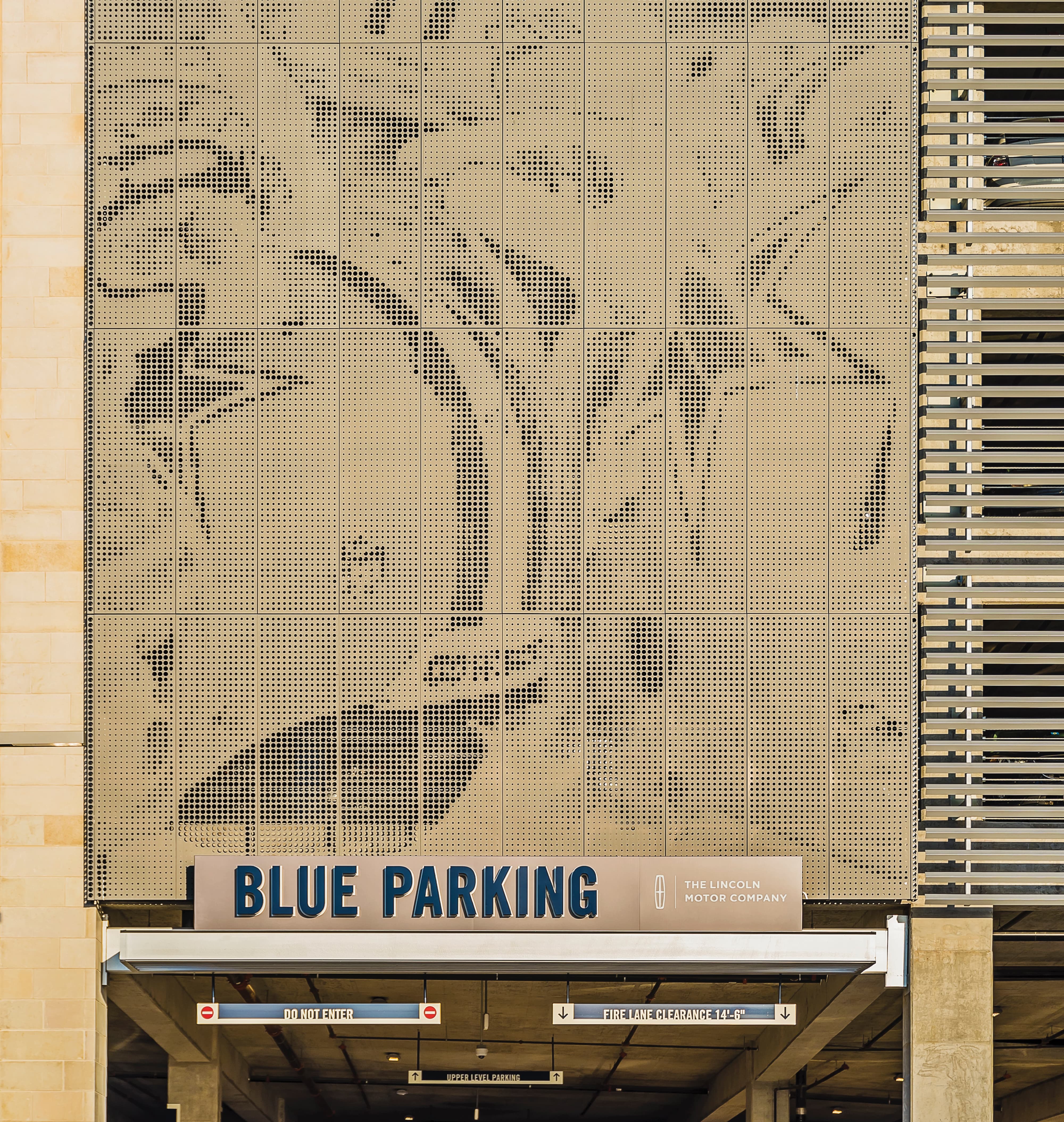 Parking garage facade featuring large-scale perforated metal architectural graphics with an abstract equestrian pattern, paired with a 'Blue Parking' identification sign and The Lincoln Motor Company branding — an example of RSM Design's experiential graphics and placemaking for a sports and entertainment mixed-use destination.
