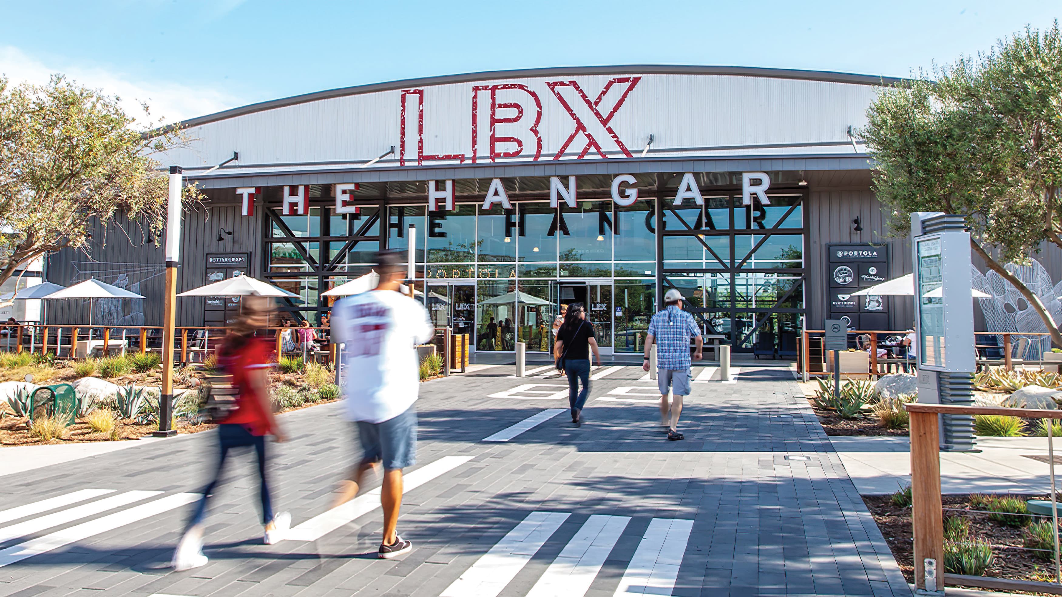 People approach hangar style building with massive painted "LBX" identity and dimensional "The Hangar" channel letters