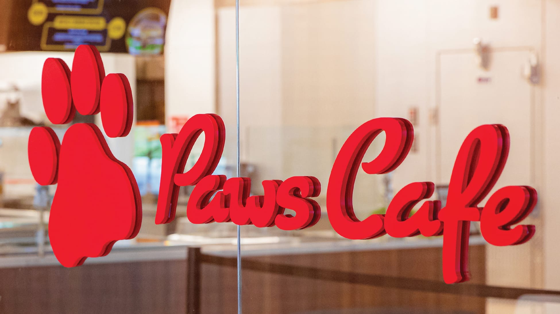 RSM Design Chapman University Rinker Campus Center Irvine — Paws Cafe dimensional red logo signage with paw print icon mounted on glass storefront, campus dining environmental graphic design