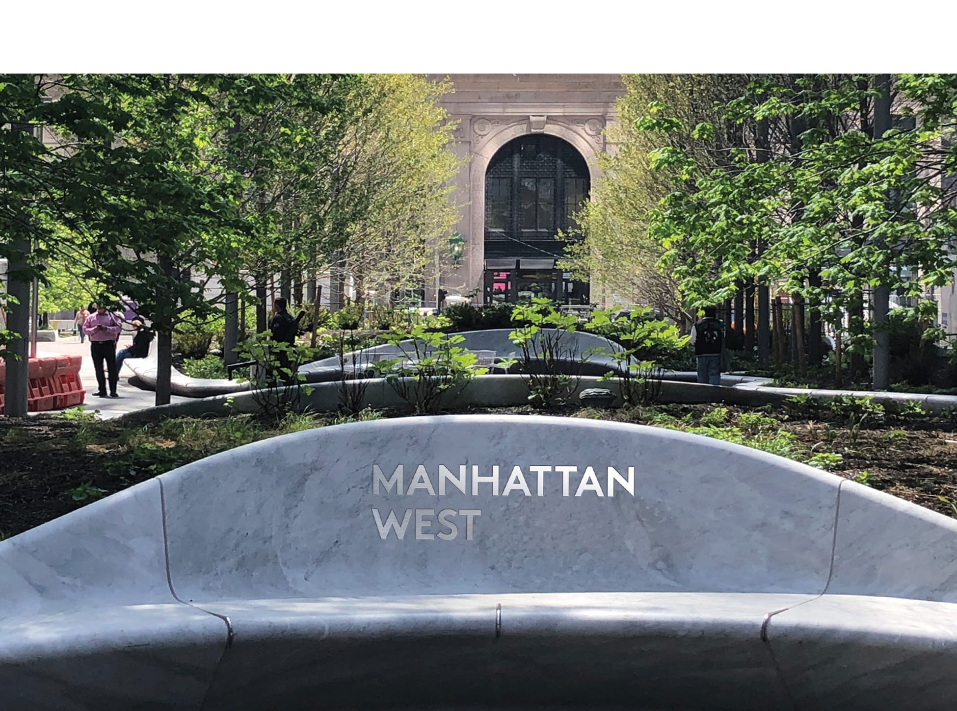 Curved marble bench engraved with "Manhattan West" in a tree-lined plaza - environmental graphic design by RSM Design