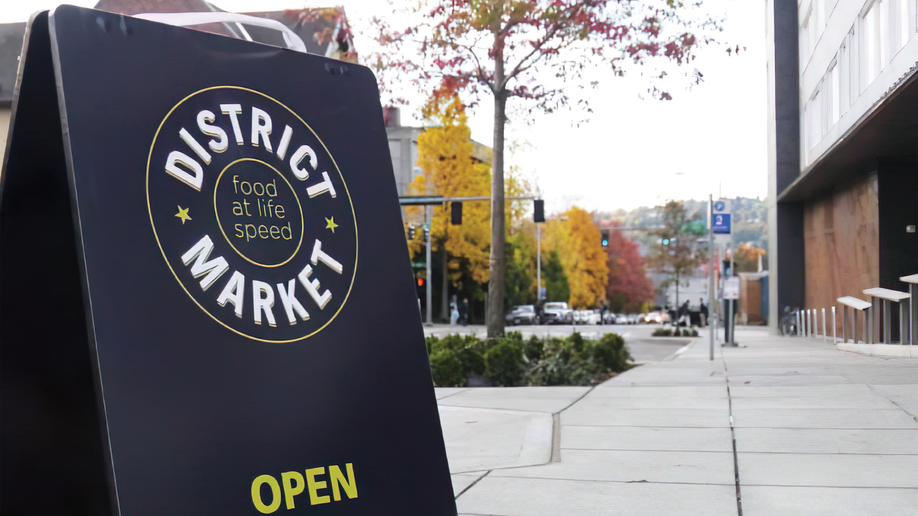 A photograph of an A-frame sign with District Market logo.