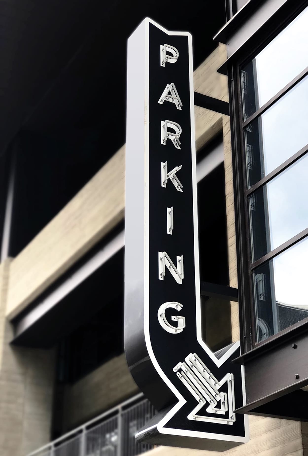 Vertical “Parking” blade sign at Fifth + Broadway, using bold typography and integrated lighting to clearly mark parking access within the district.