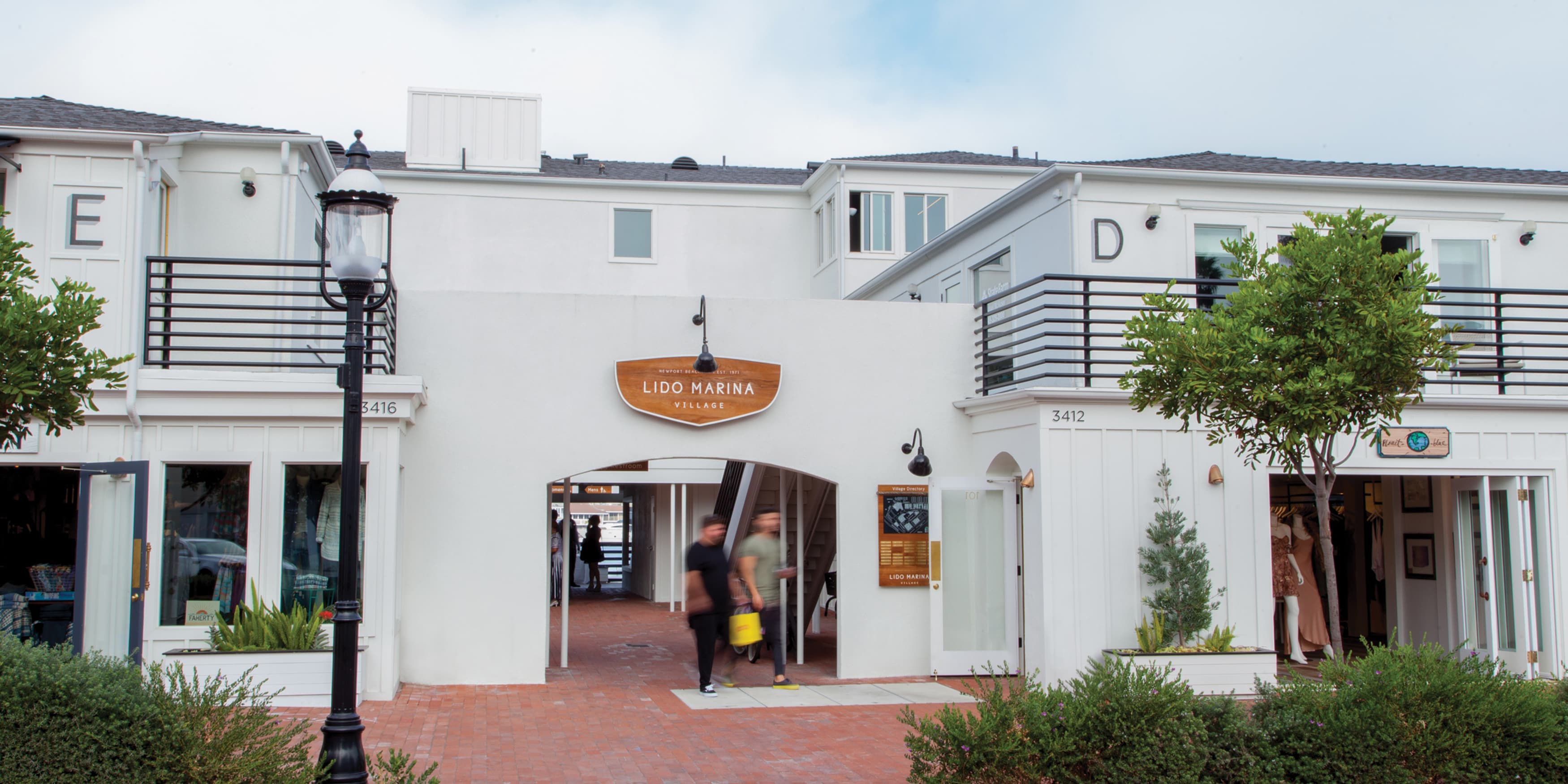 Image of two people walking out of the shopping destination, Lido Marina Village in Newport Beach, California. Designed by RSM Design. 