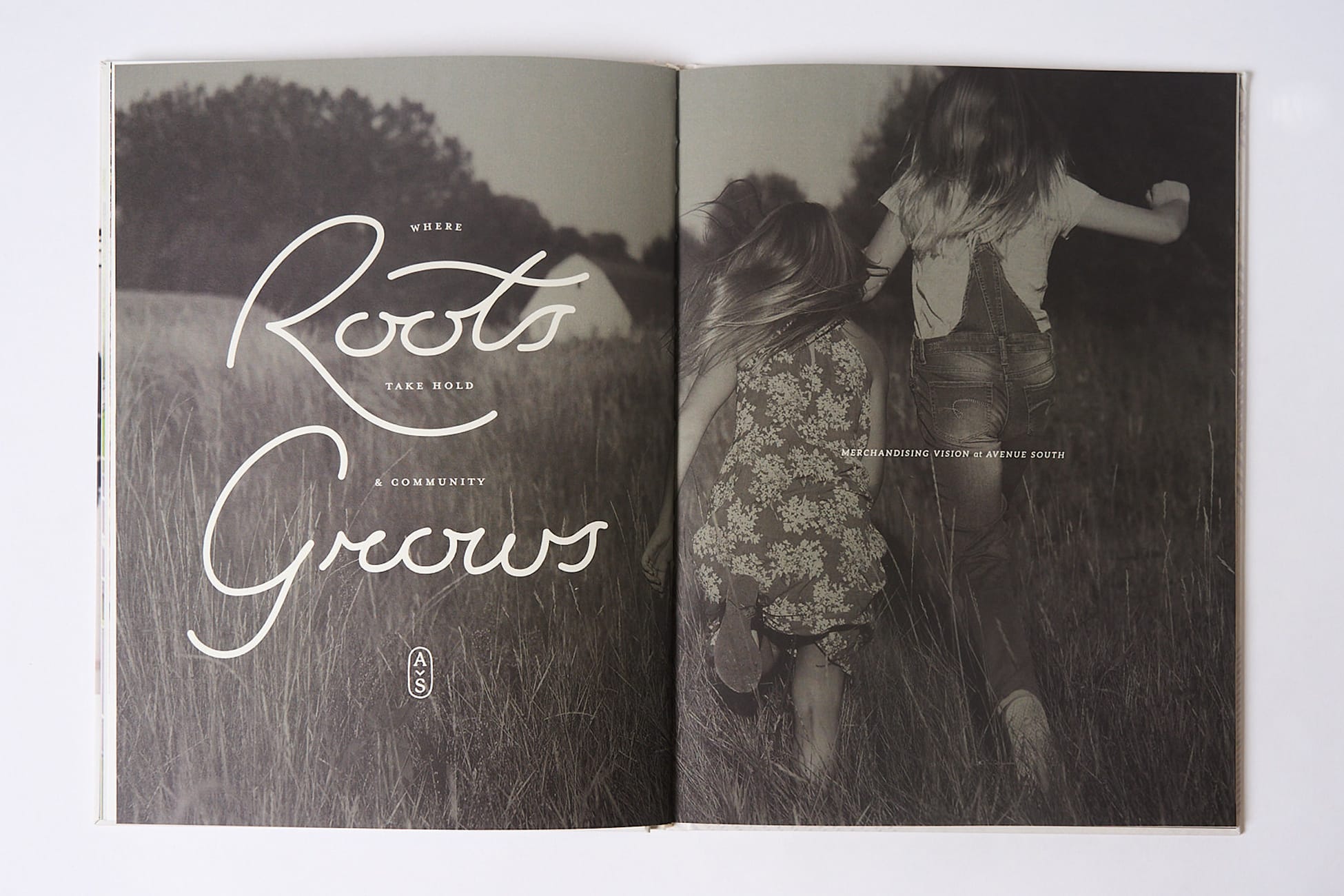 Open book spread with "Where Roots Take Hold and Community Grows" script headline beside black and white photo of children running through a field, merchandising vision brand identity by RSM Design.