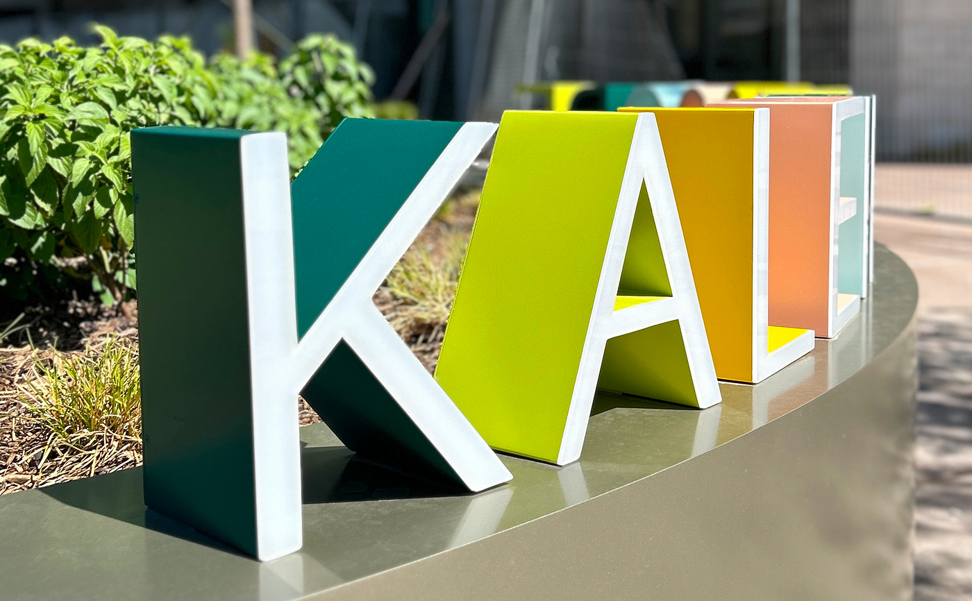 Close-up detail of multicolored dimensional letter sculpture spelling "Kaleidoscope" in teal, lime green, orange, and white at Kaleidoscope Park public plaza, Frisco, Texas