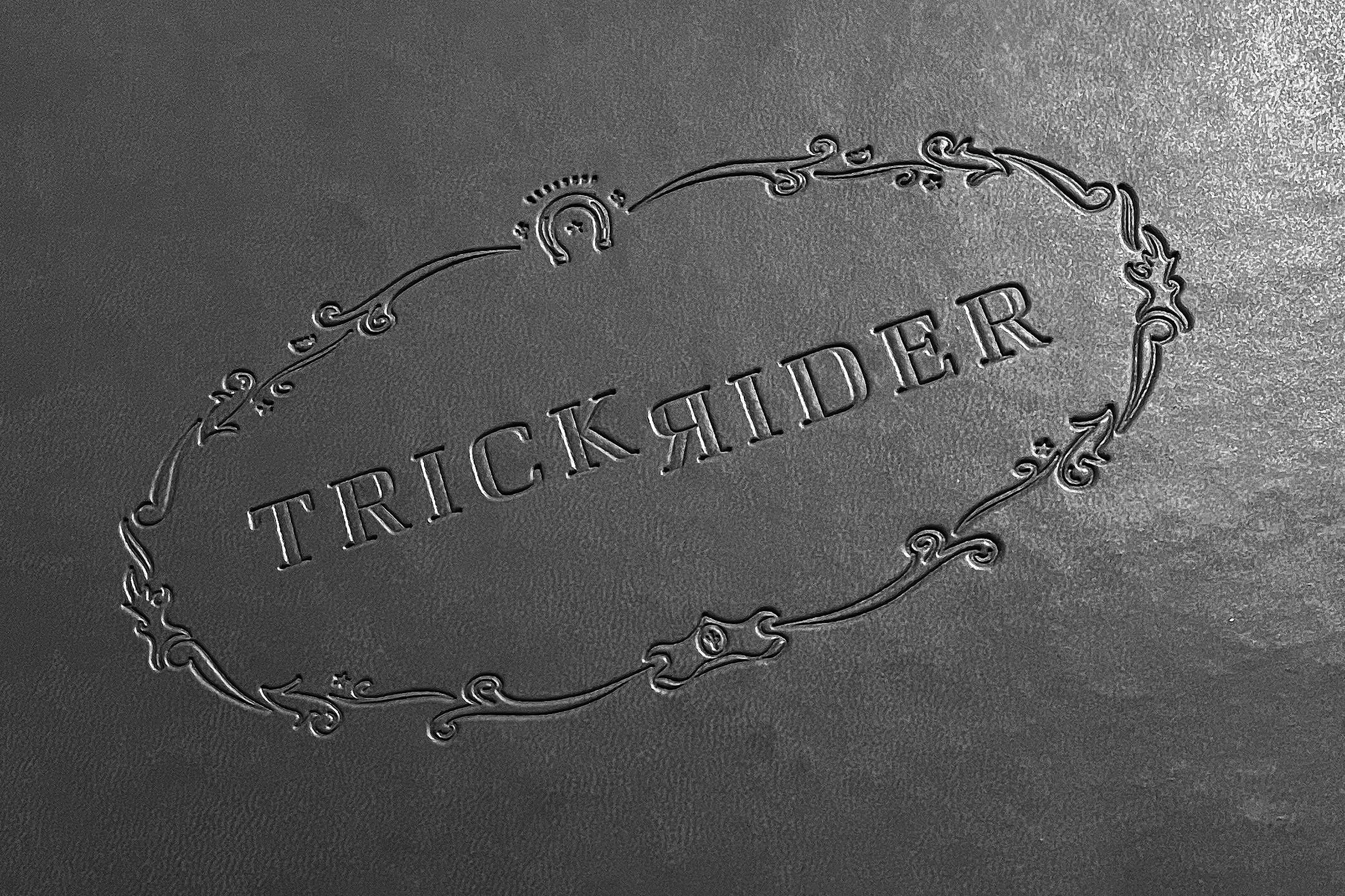 Trick Rider ornate oval emblem embossed on black leather with horseshoe and scrollwork details, Omni PGA Frisco Resort, brand identity by RSM Design.
