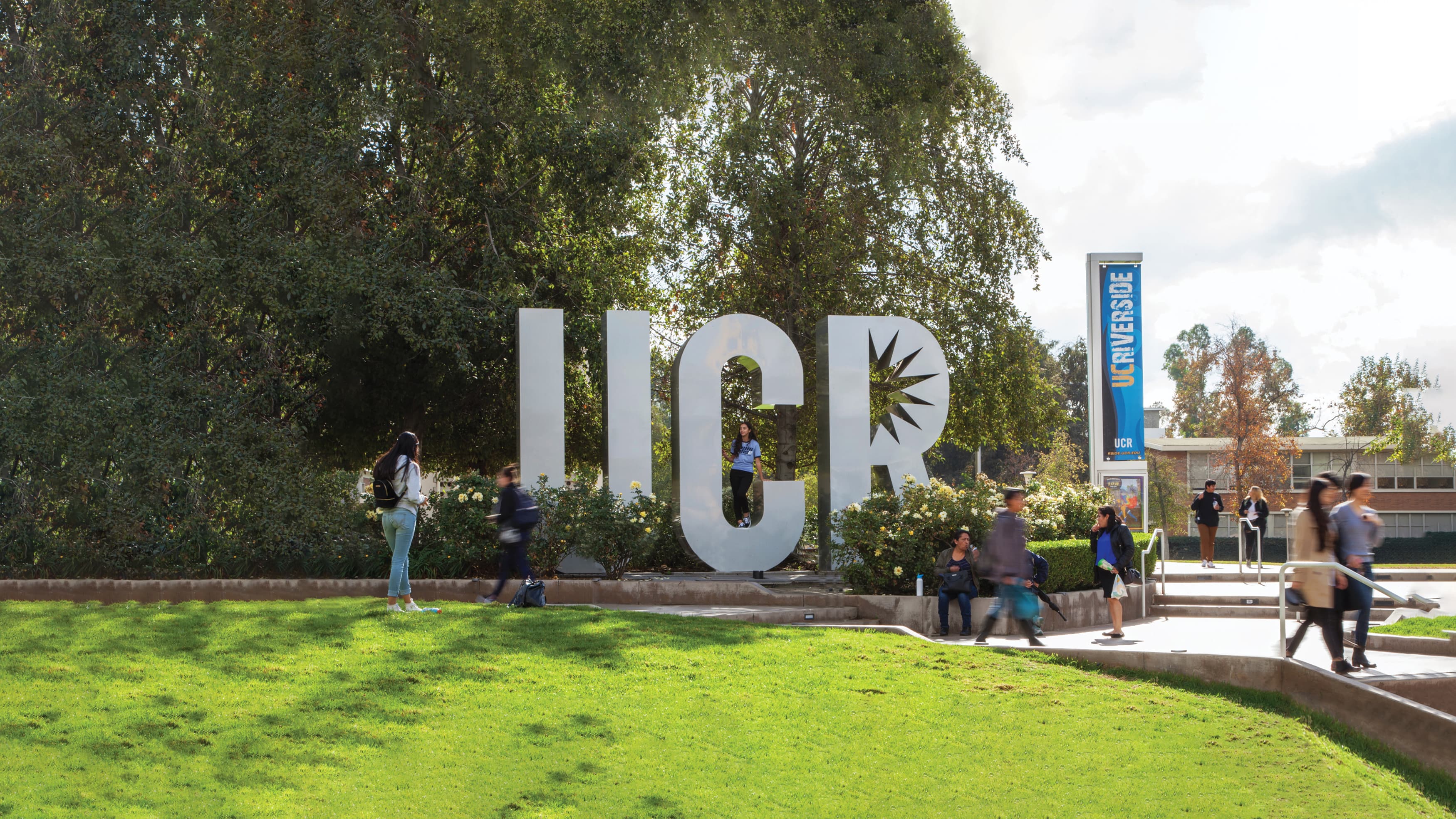 UC Riverside quad with sculptural UCR letters and students bustling