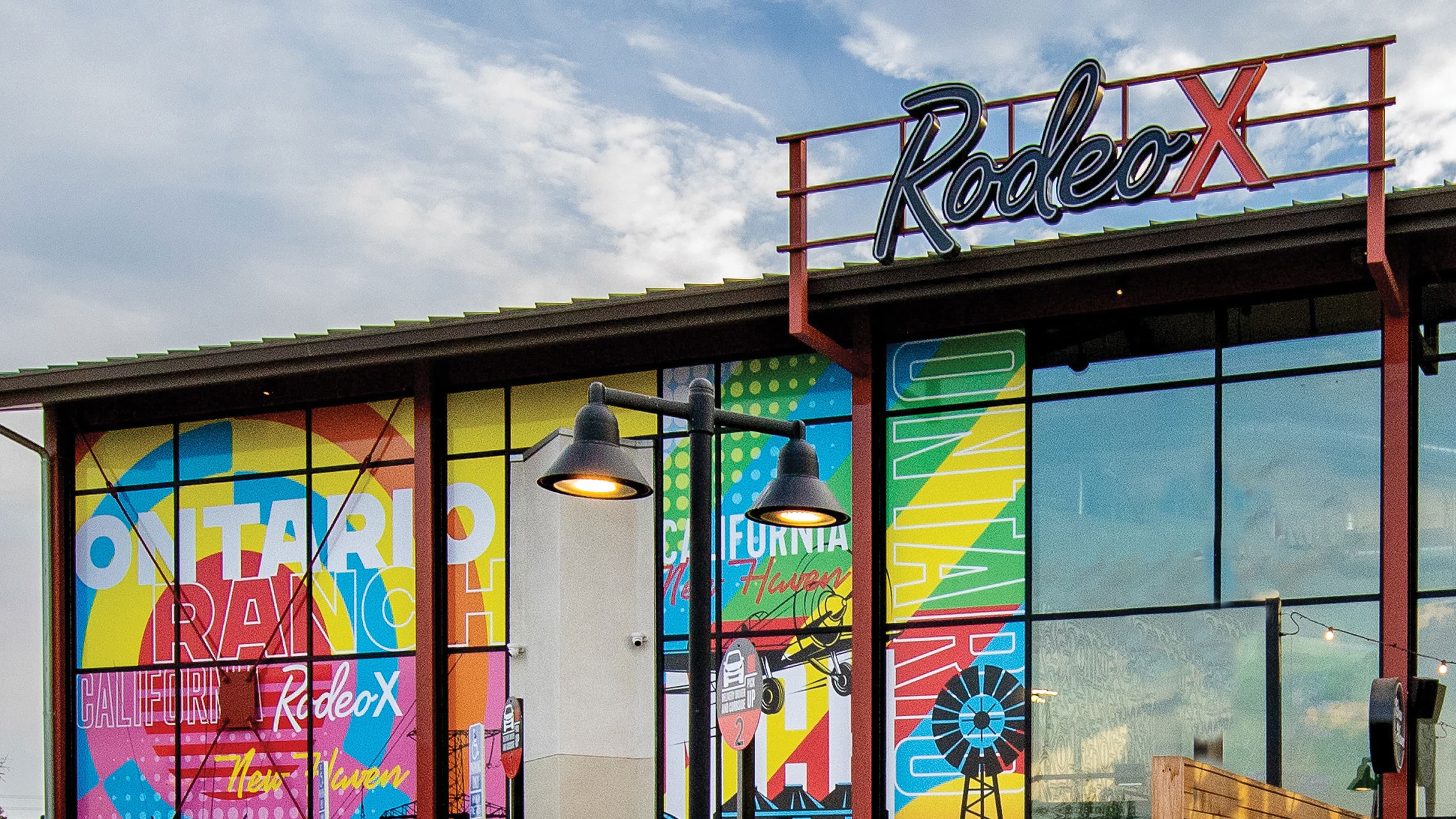 Rooftop neon signage with red structure for support with glass facade of colorful graphics