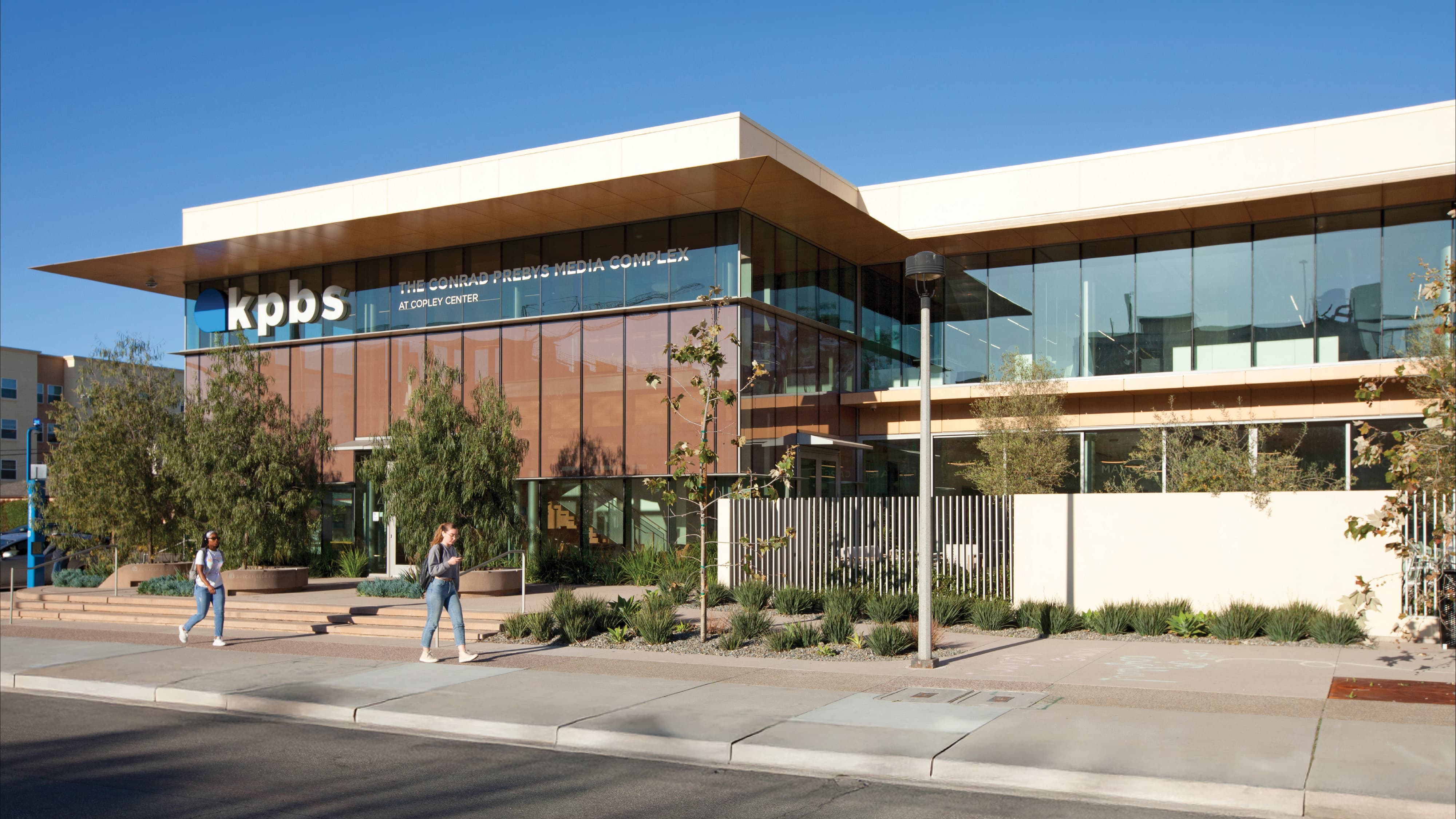 Contemporary media campus building featuring KPBS at the Conrad Prebys Media Complex in San Diego, showcasing integrated environmental graphic design, branded signage, and wayfinding within a civic and education environment, highlighting RSM Design expertise in placemaking, identity, and experiential design for cultural and institutional markets.