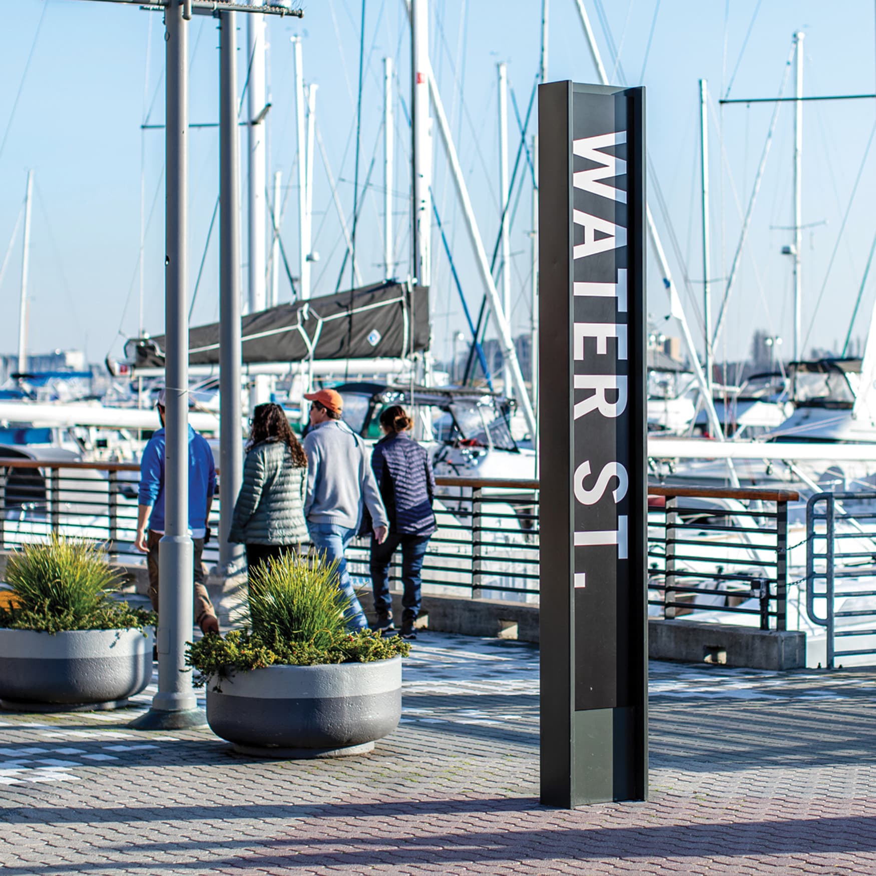 Waterfront wayfinding signage on the boardwalk with boats docked in the background