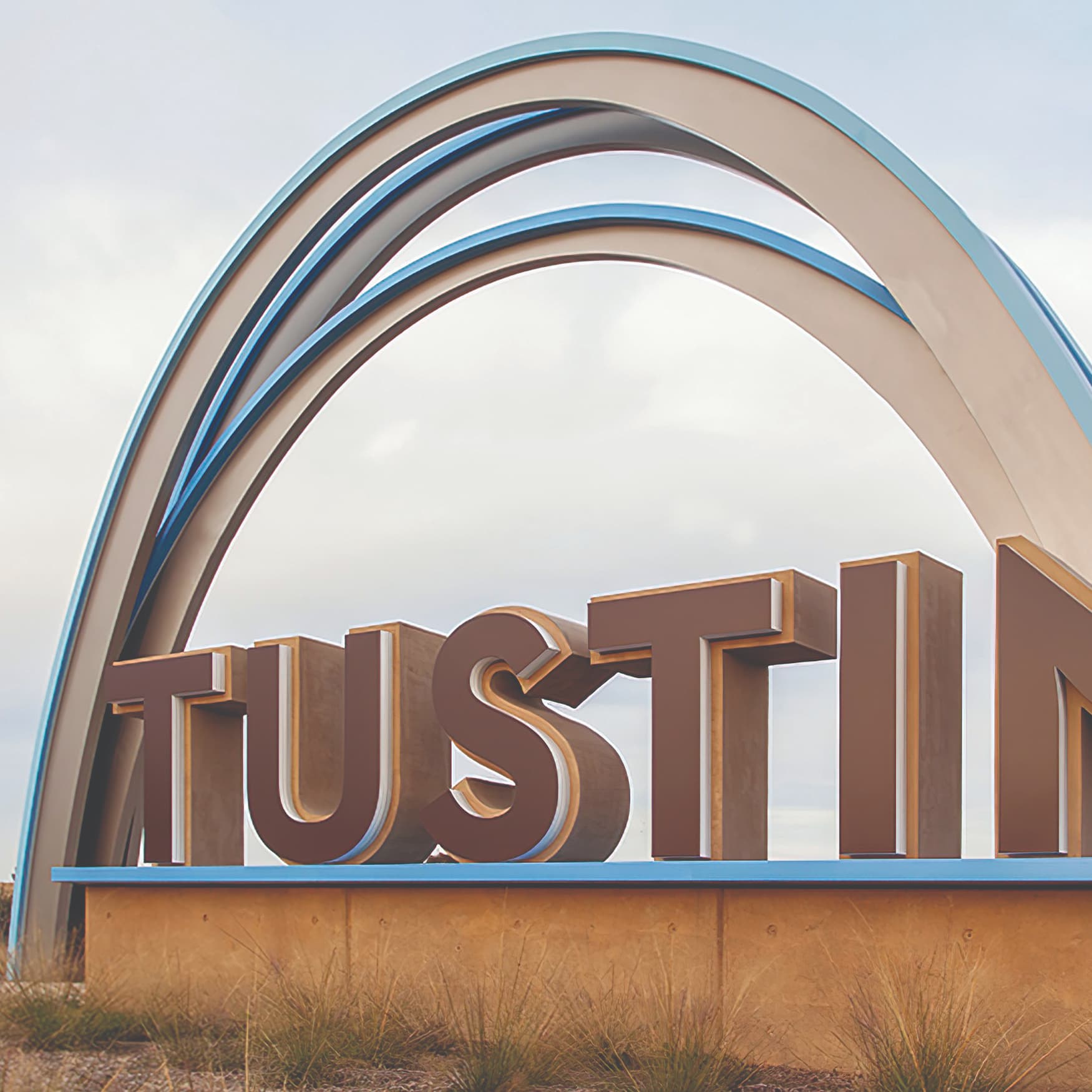A photograph of a monument sign at Tustin Legacy featuring an arch and large fabricated letters.