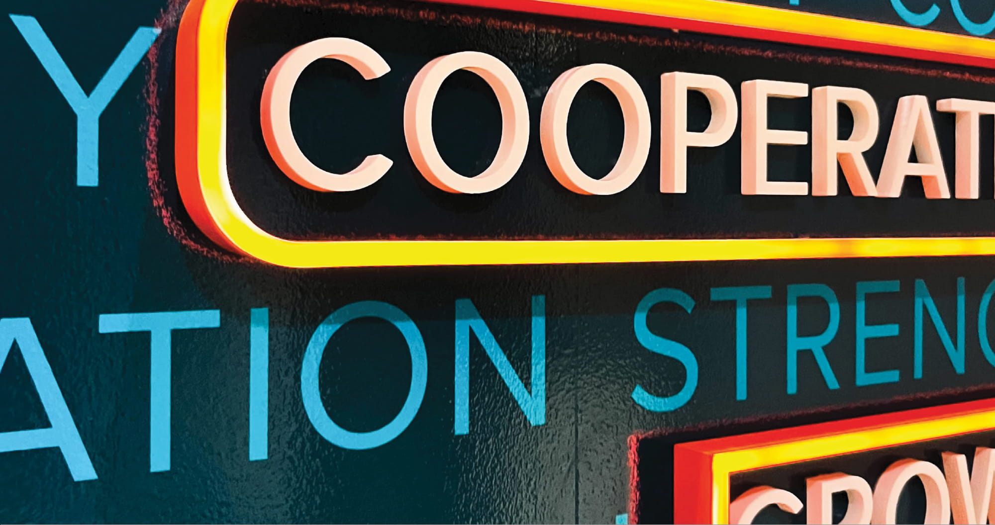 Illuminated environmental graphic signage with dimensional typography and neon accents, showcasing brand identity design and experiential graphics within a workplace or retail environment, supporting placemaking, wayfinding, and branded customer experience.
