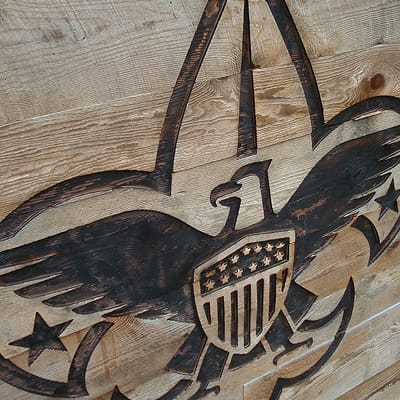 Close-up of carved and charred Boy Scouts of America eagle emblem on reclaimed wood wall at Summit Bechtel Reserve, detailed environmental graphic and signage craftsmanship by RSM Design