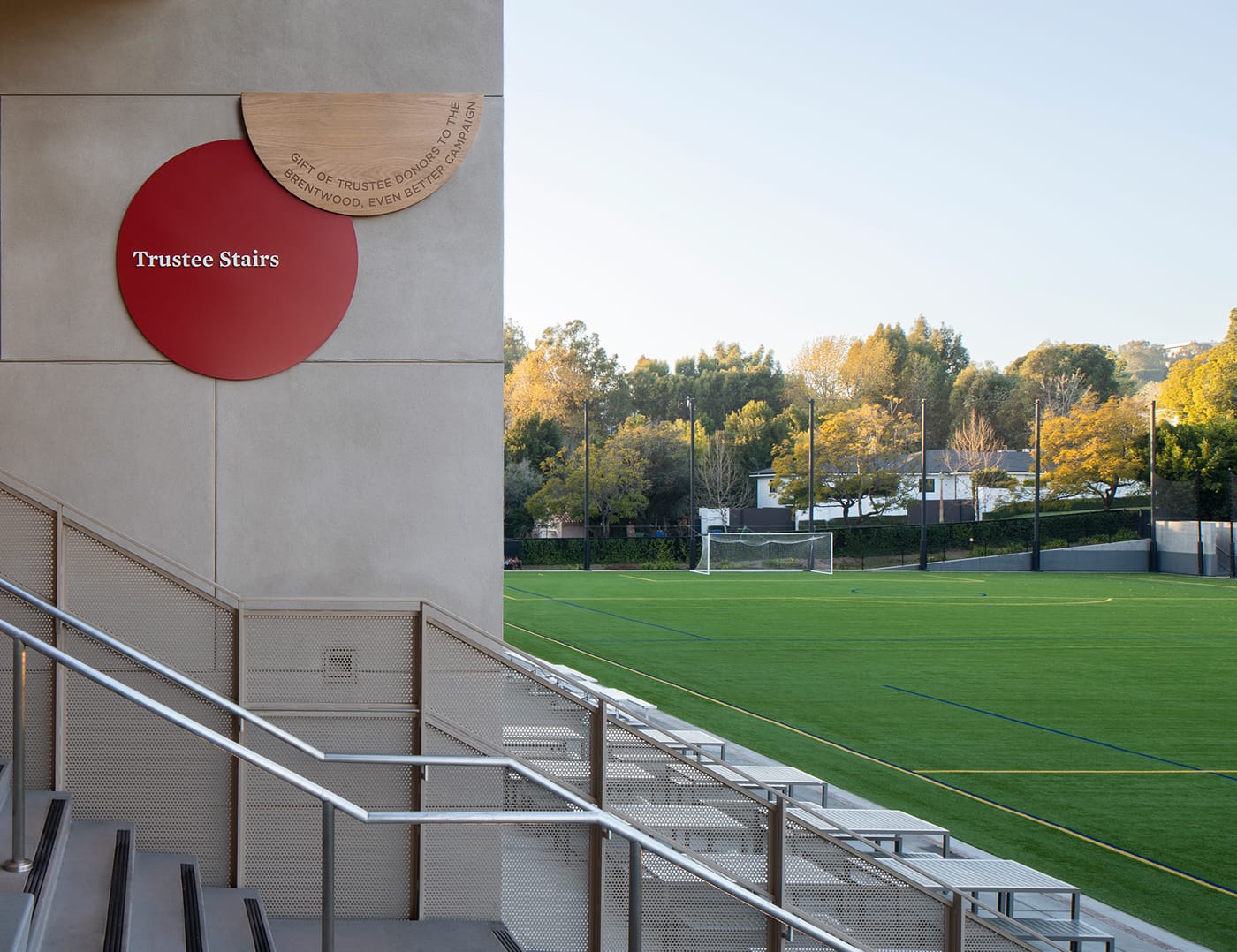 Trustee Stairs donor sign overlooking athletic field bleachers at Brentwood School campus in Los Angeles - donor recognition and environmental graphic design by RSM Design