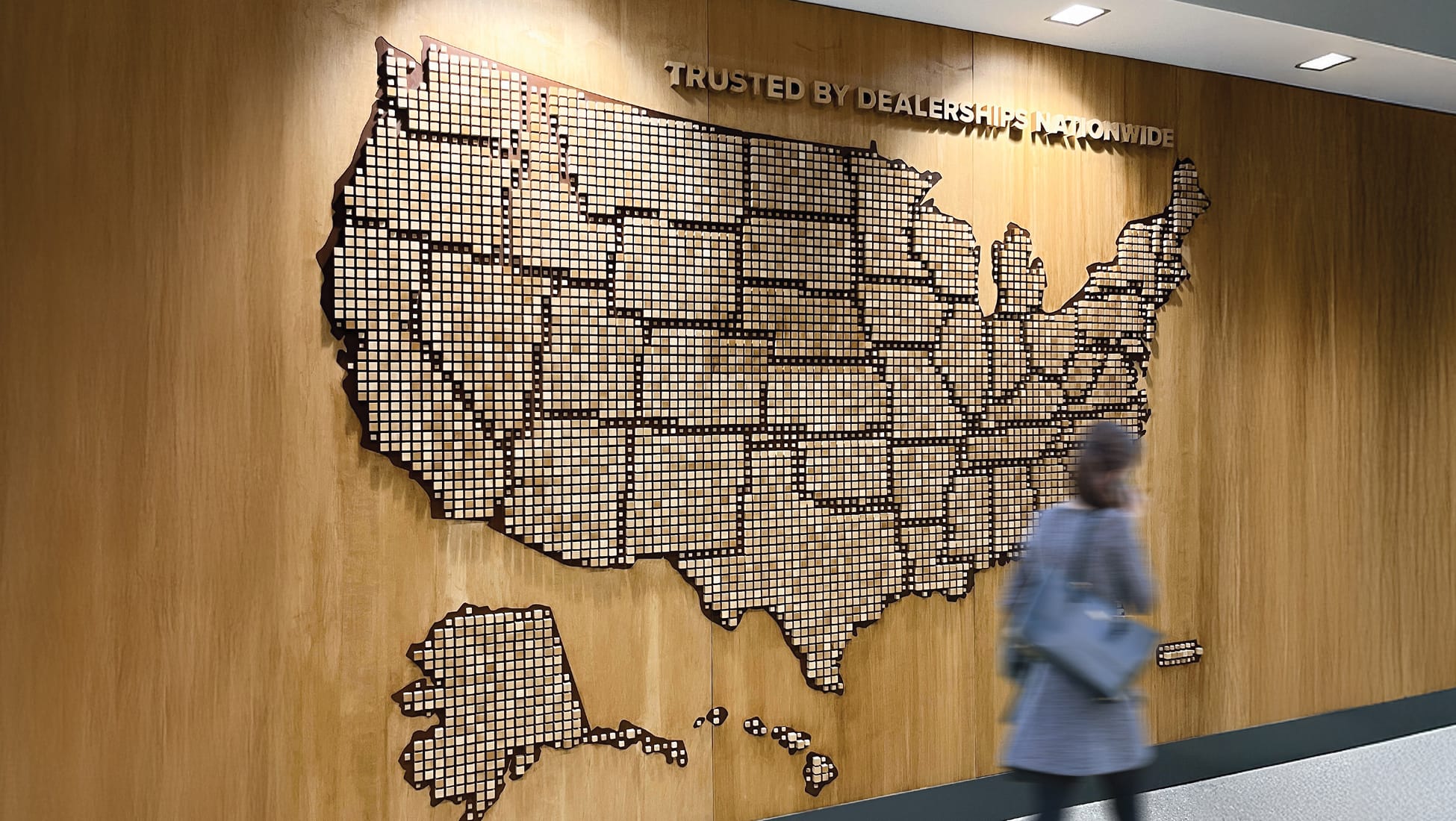 Environmental graphic design feature wall displaying a large U.S. map installation, integrating branded storytelling and placemaking within a corporate workplace, supporting experiential design, wayfinding, and brand identity for a national automotive client.