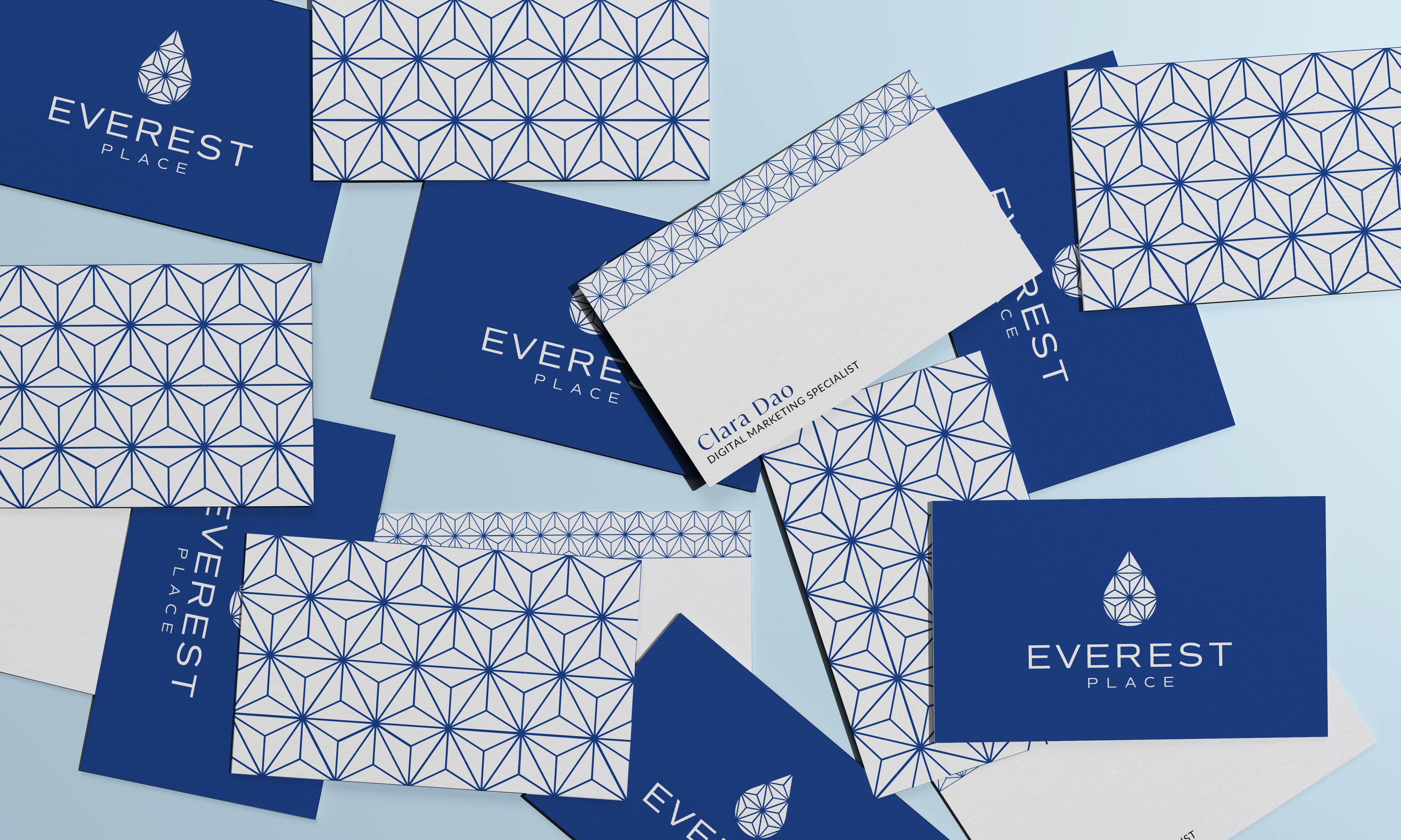 Blue and white business cards scattered on a table with the Everest Place logo.