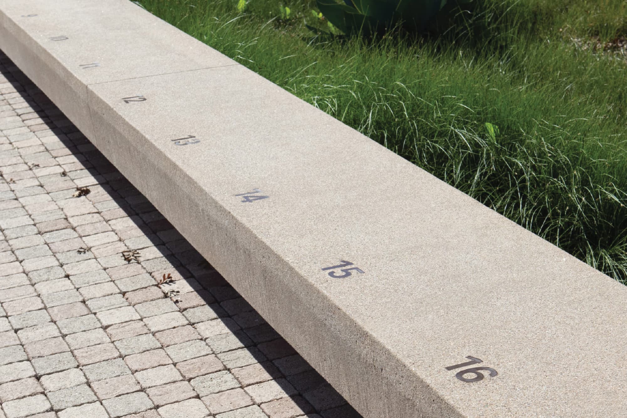 Cast-in-place concrete seating with integrated numbering detail, illustrating environmental graphic design, donor recognition, and placemaking within an outdoor public space and mixed-use campus by RSM Design
