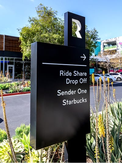 Directional wayfinding signage at Runway Playa Vista guiding visitors to rideshare drop-off, retail, and dining destinations, designed by RSM Design as part of the district’s environmental graphics system.