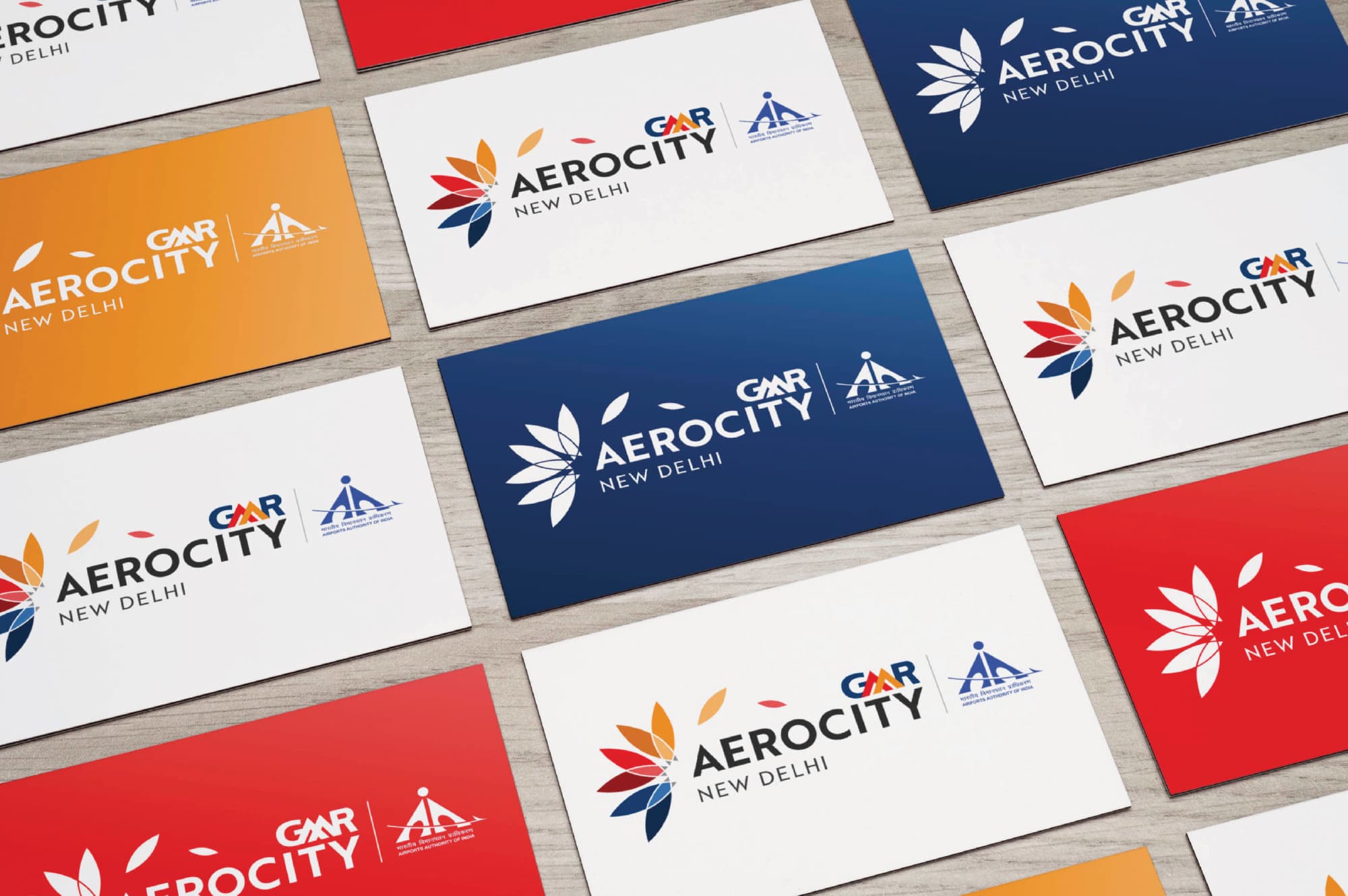 GMR Aerocity New Delhi branded business card collection displayed as a flatlay showcasing multiple logo colorway variations across white, navy, orange, and red backgrounds with the multicolored lotus flower brand mark and Airports Authority of India co-branding — RSM Design branding and visual identity, print and digital collateral, and specialty graphics for mixed-use, transit, and international destinations.