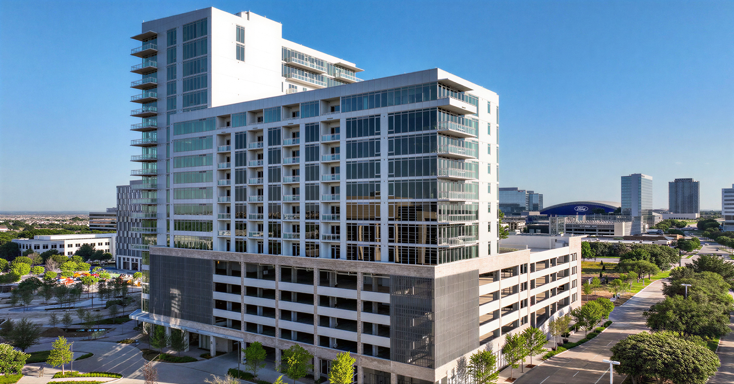 Alt Text:
Monarch at Hall Park luxury high-rise apartment tower in Frisco, Texas — modern glass and white facade residential development by RSM Design, with structured parking podium and panoramic views of the Dallas-Fort Worth skyline