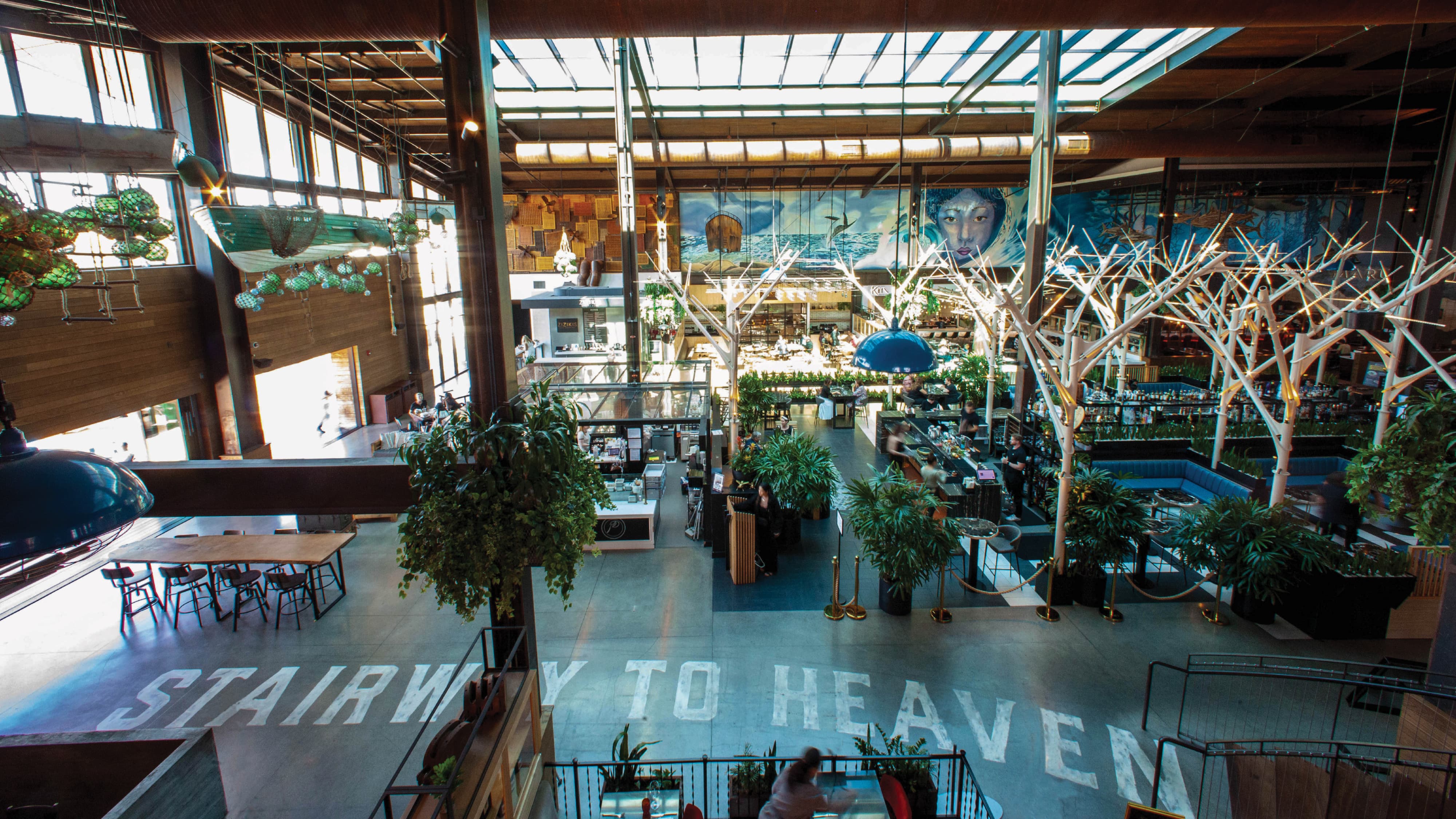Environmental graphic design within a high-end hospitality and mixed-use destination, featuring large-scale architectural graphics, branded placemaking, and integrated wayfinding in an open-concept food hall environment. The space showcases experiential design, custom lighting installations, and immersive storytelling elements that enhance circulation, guest experience, and tenant identity within a retail and entertainment setting.
