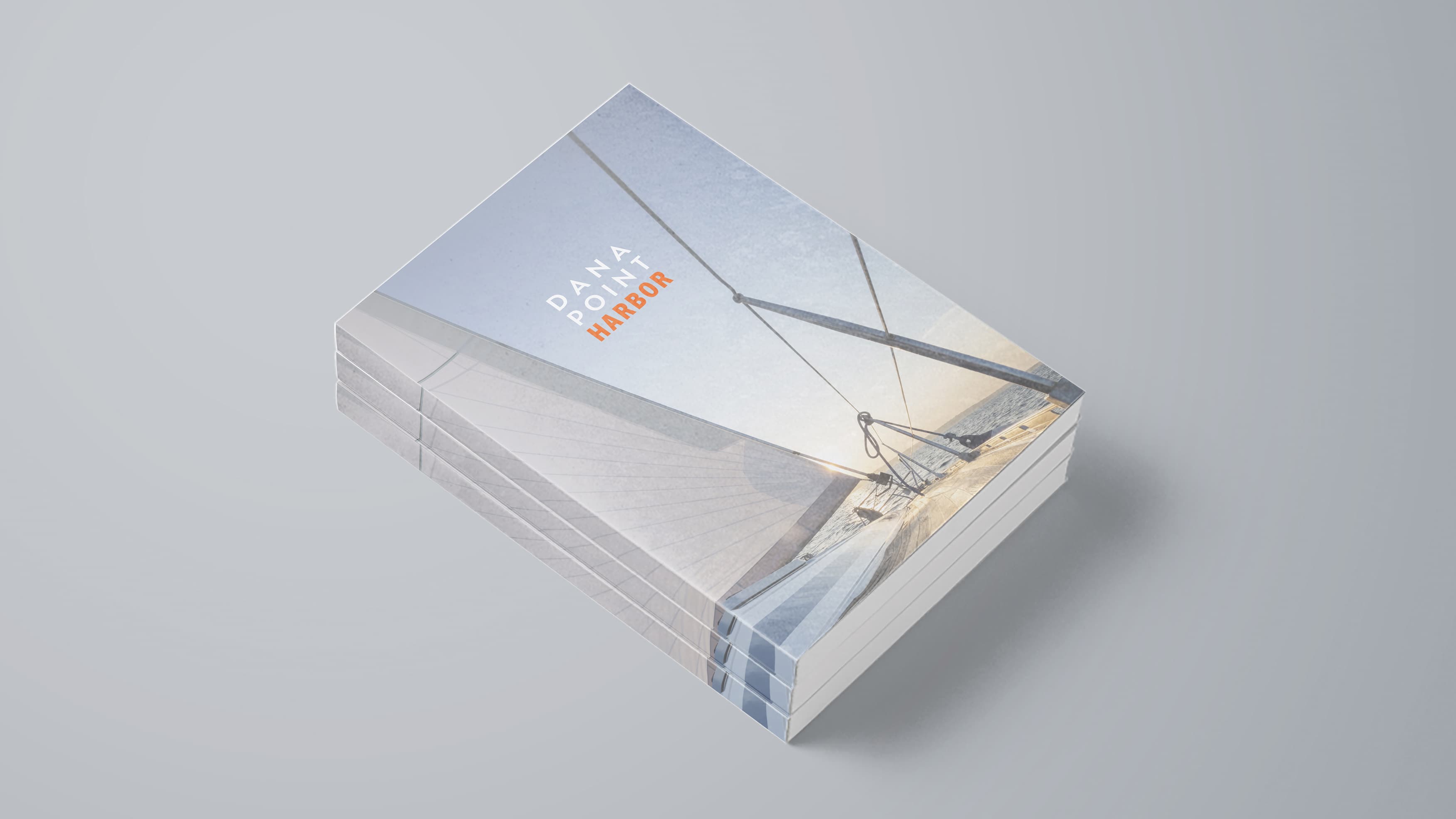 Mockup of the cover of a Dana Point Harbor leasing brochure with logo and sailboat image in the background
