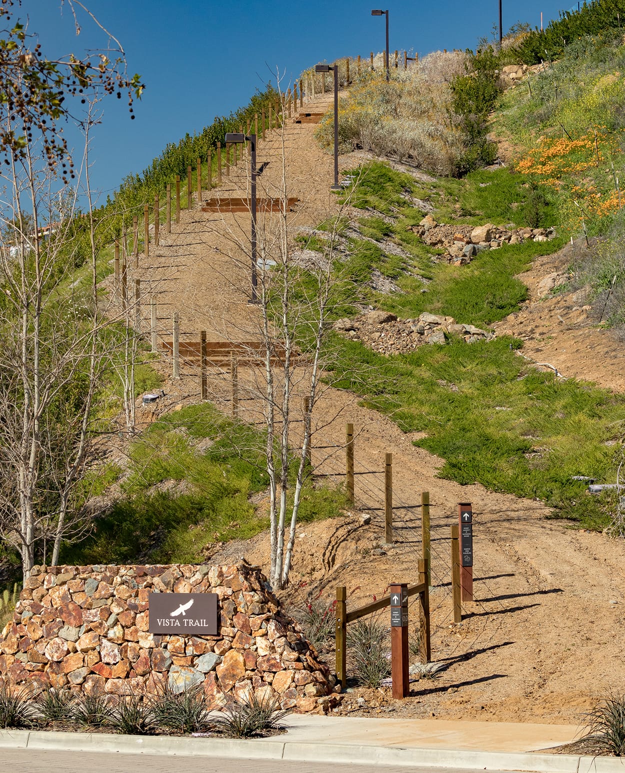 "Vista Trail" stone-set trailhead sign with bird icon at the base of a hillside path at Terramor - environmental graphic design by RSM Design