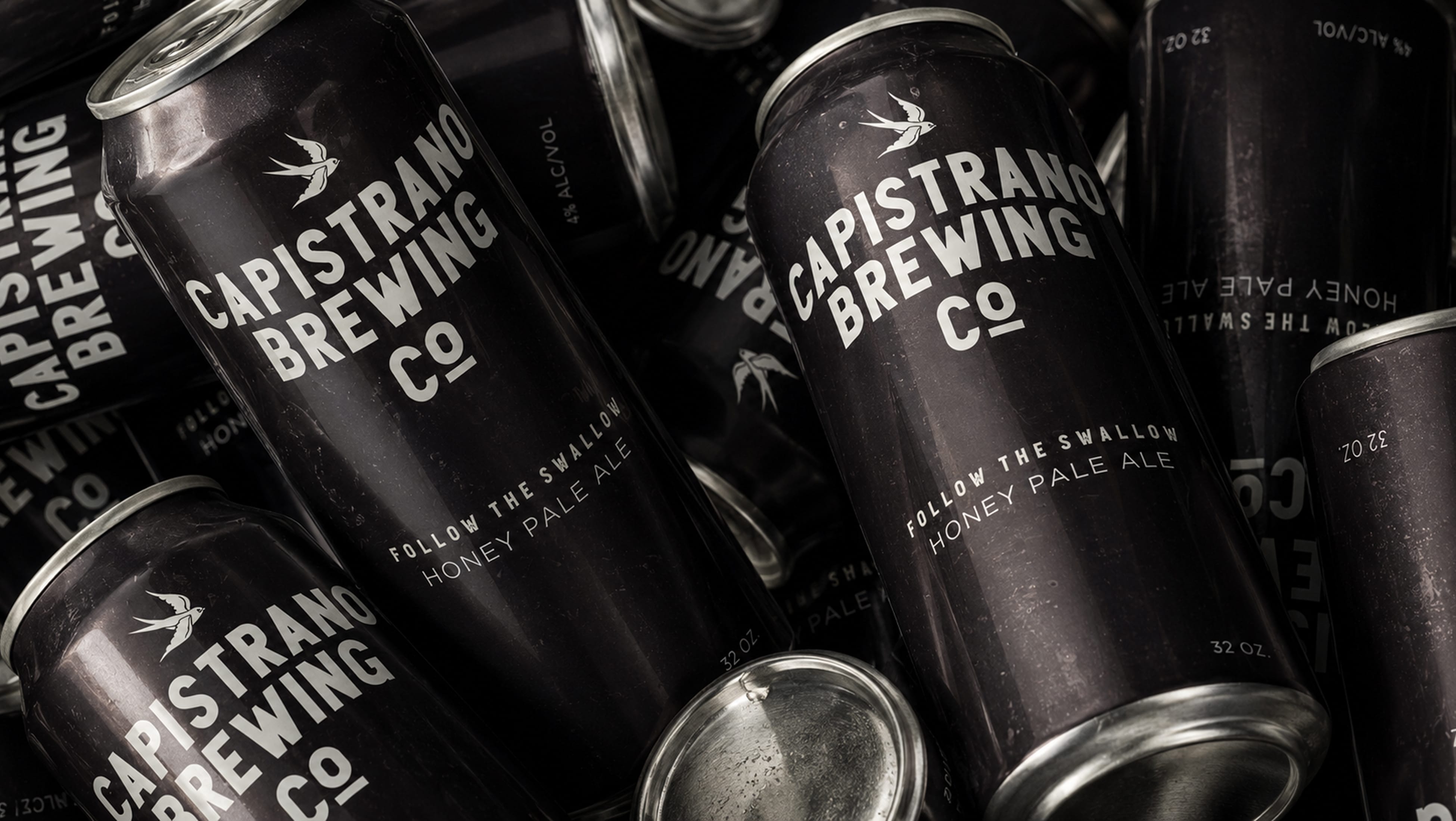 Black matte cans of Capistrano Brewing Co. Honey Pale Ale featuring a swallow icon and "Follow the Swallow" tagline, brand identity design by RSM Design