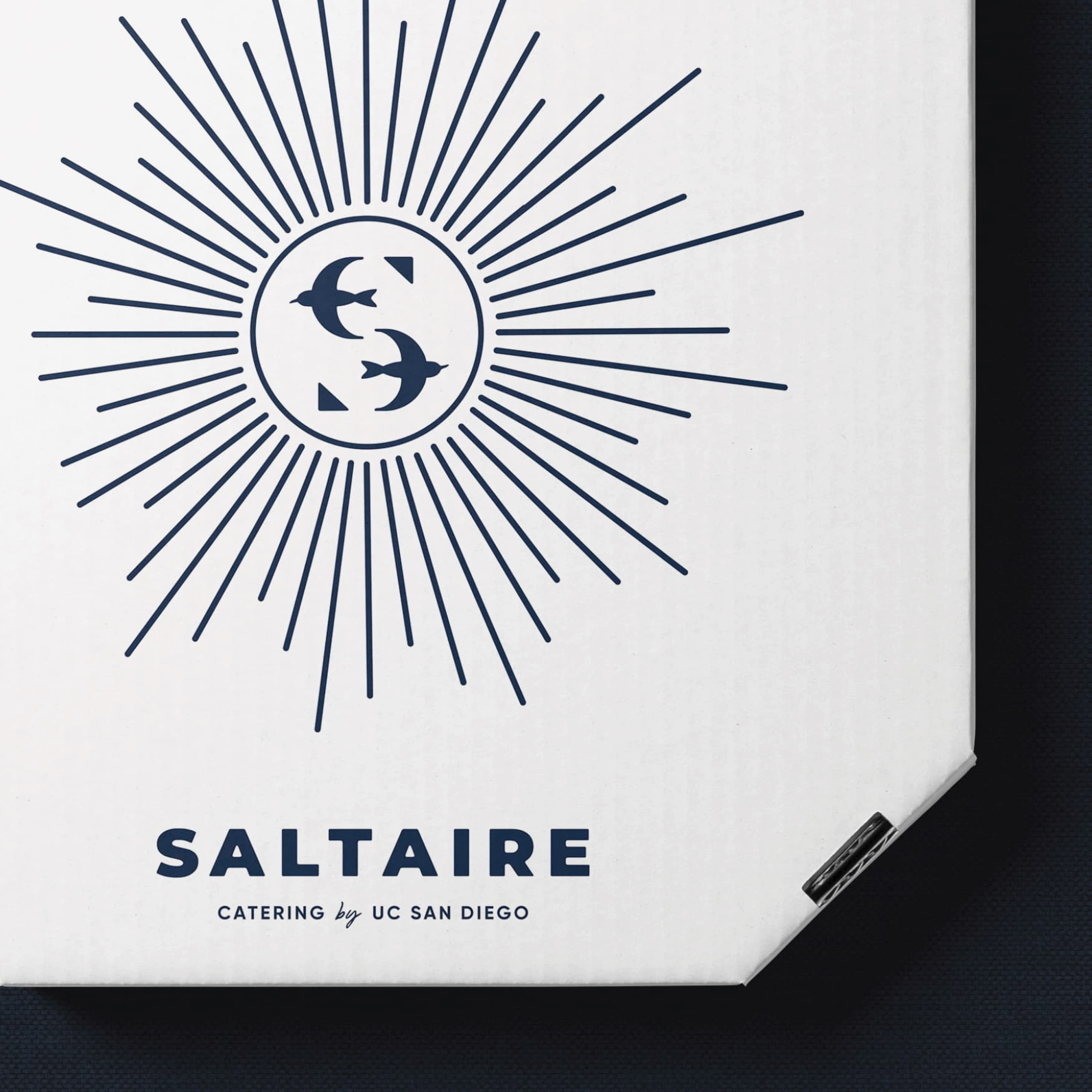 Saltaire Catering by UC San Diego branded box featuring the tern lettermark inside a sunburst illustration in navy on white, showcasing specialty graphics and print collateral design for a food and beverage and education market client by RSM Design.