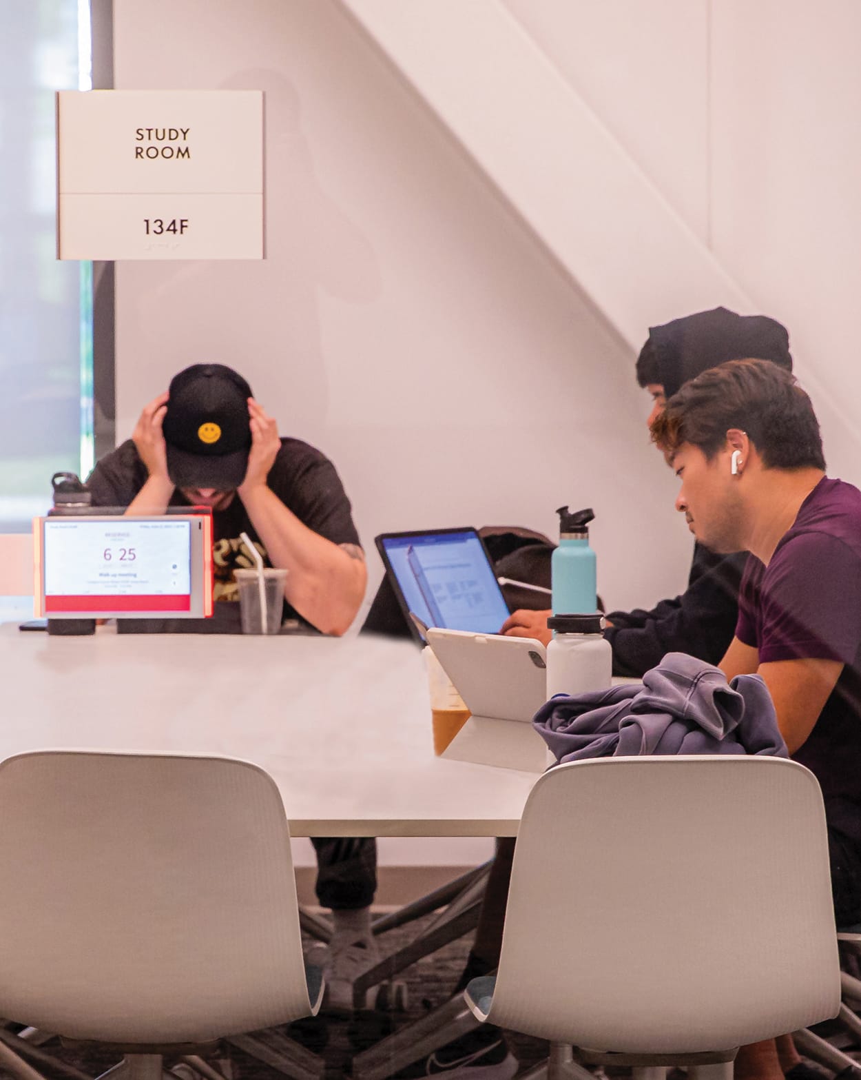 RSM Design Chapman University Rinker Campus Center Irvine — students studying in active campus study room with overhead room identification signage and integrated room booking display tablet