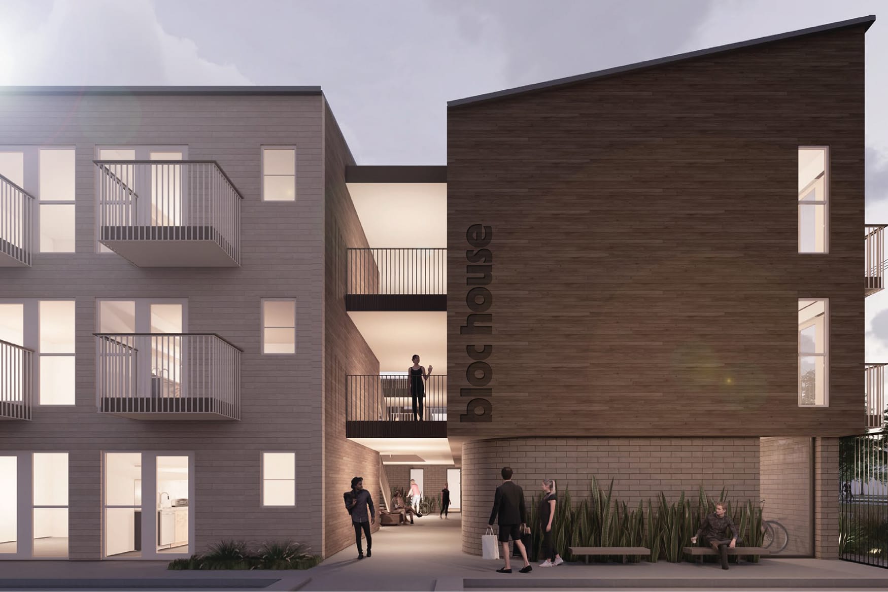 Dusk rendering of the Bloc House courtyard in Dallas, showing two multi-story residential buildings flanking a lit pedestrian passage. The left building features light brick cladding with balconies and floor-to-ceiling windows glowing warmly from within; the right building is clad in horizontal wood siding with the "bloc house" wordmark mounted vertically. Residents gather at ground level and on an upper walkway connecting the two wings, with ornamental grasses and a bicycle visible along the perimeter.
