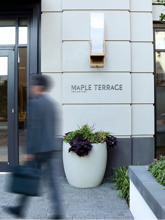 "Maple Terrace Residences" sign on the building facade beside the entrance and planter - environmental graphic design by RSM Design