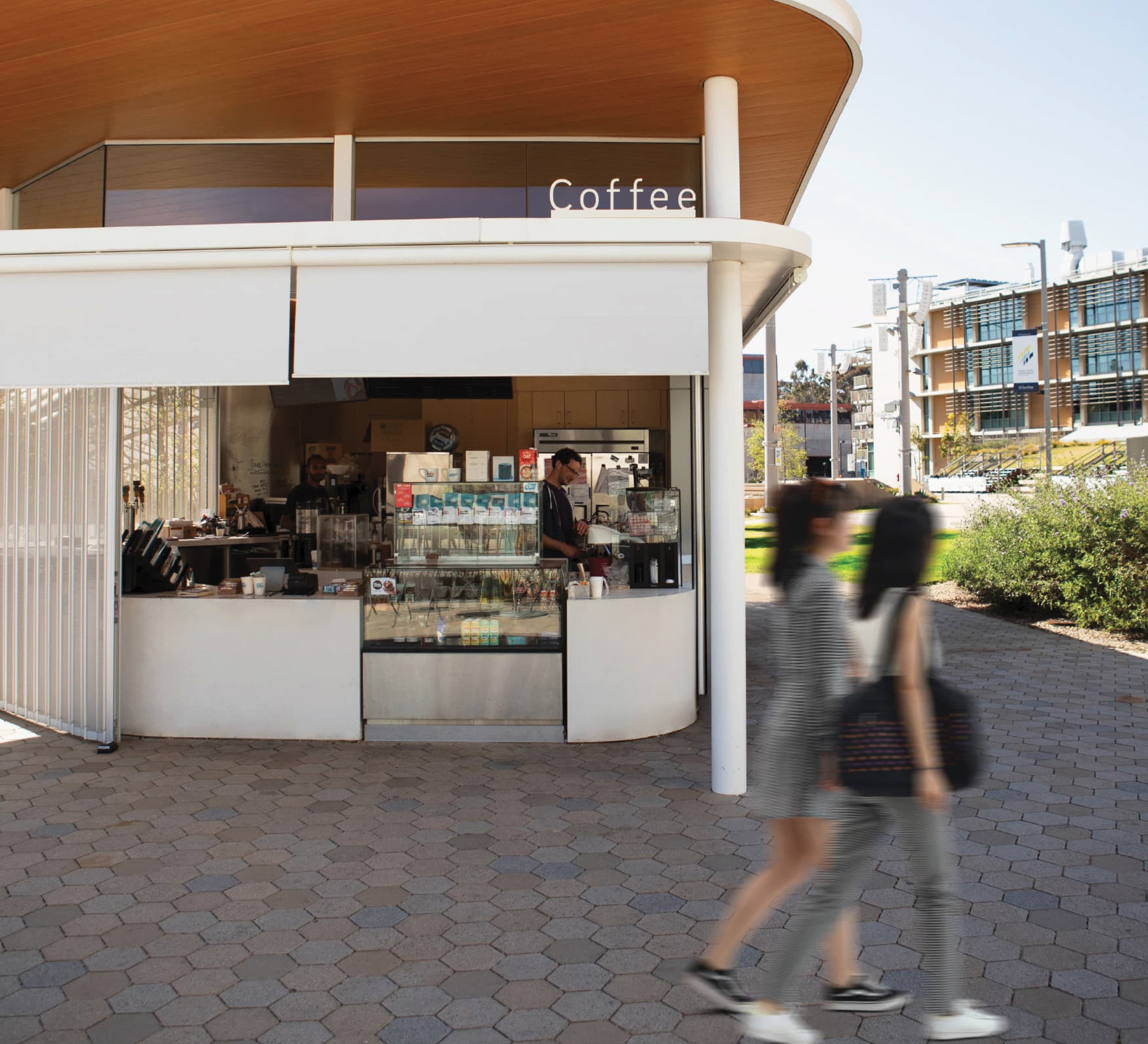 Outdoor coffee kiosk within a mixed-use urban district, featuring integrated environmental graphic design, branded signage, and placemaking for retail and hospitality environments by RSM Design