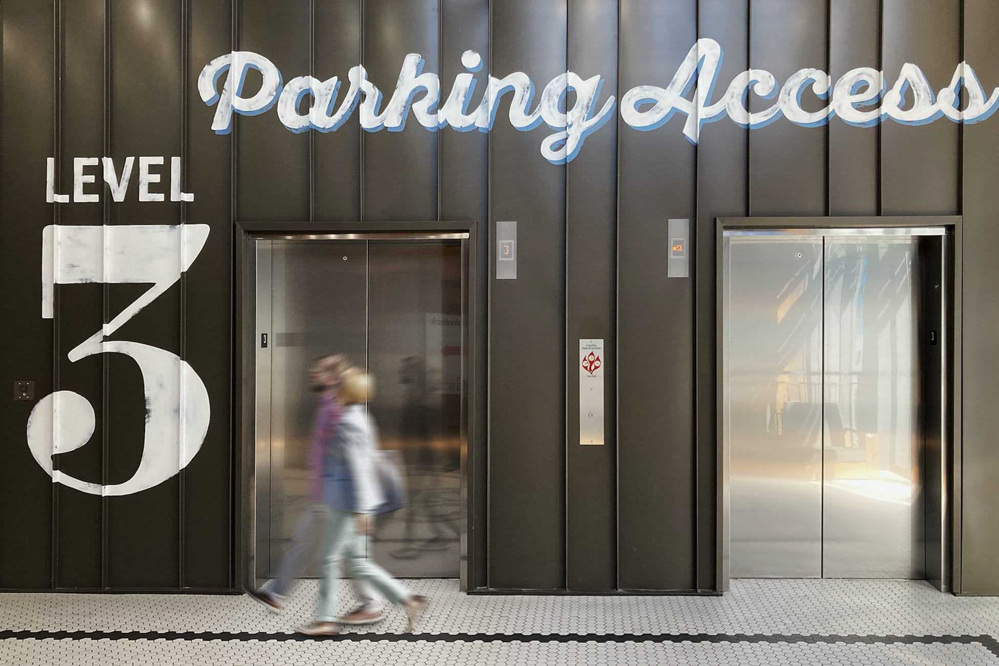 Elevator lobby at Fifth + Broadway with large-scale “Level 3” wayfinding graphics and integrated environmental branding guiding visitors through the space.