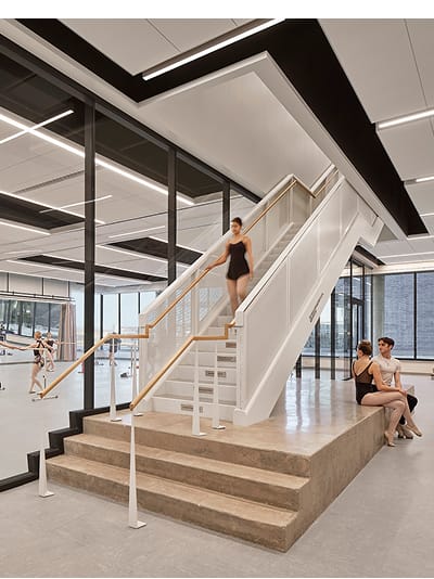 Ballet students in a modern dance studio with floor-to-ceiling windows, ballet barres, and a central staircase with glass railings at Buddy Holly Hall of Performing Arts and Sciences, Lubbock Independent School District, Lubbock Texas