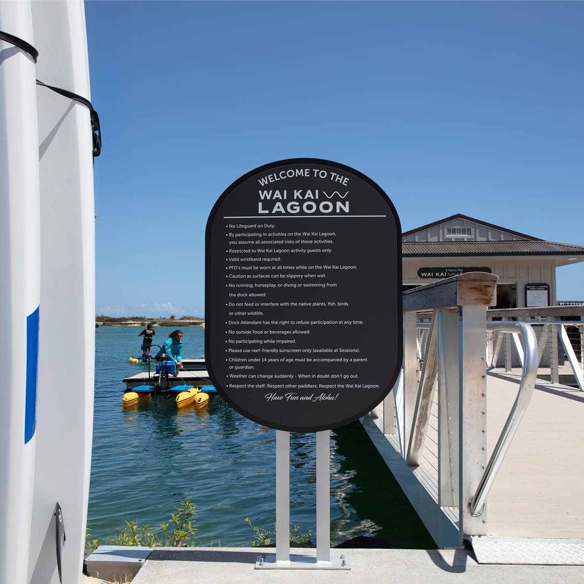 "Welcome to the Wai Kai Lagoon" regulatory sign on dock overlooking paddlers on the water, Ewa Beach, Oahu, wayfinding by RSM Design.