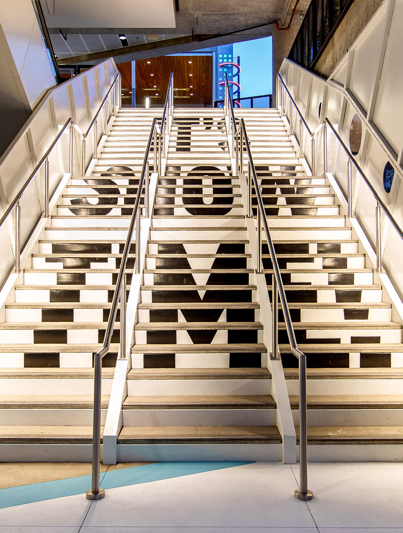 Staircase graphic at Runway Playa Vista spelling “It’s Show Time,” integrating environmental graphics and wayfinding within the mixed-use retail and entertainment district designed by RSM Design.