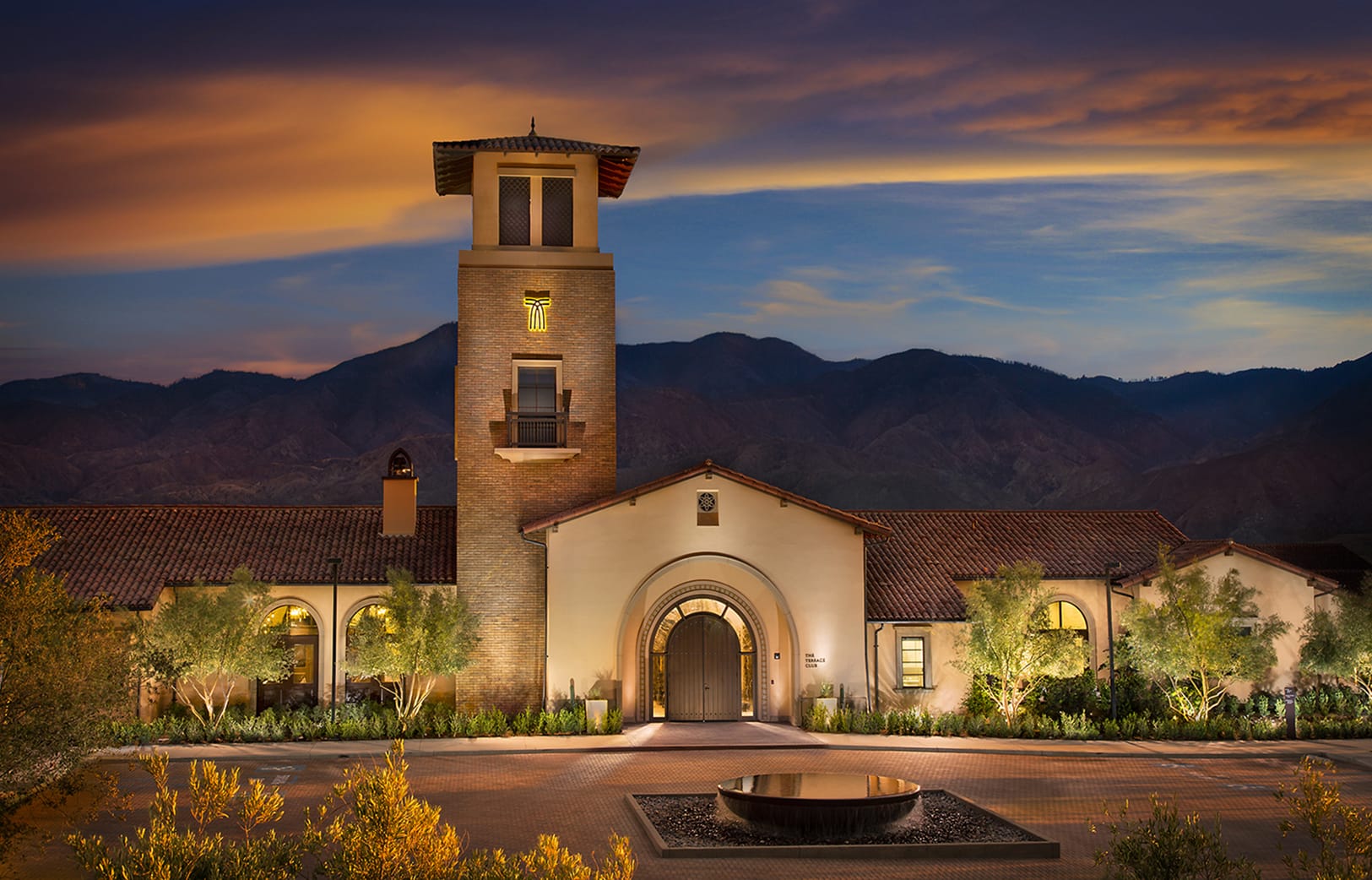 Illuminated Spanish Mission-style clocktower and archway entrance of the Terrace Club at dusk with the Terramor logo mark - environmental graphic design by RSM Design
