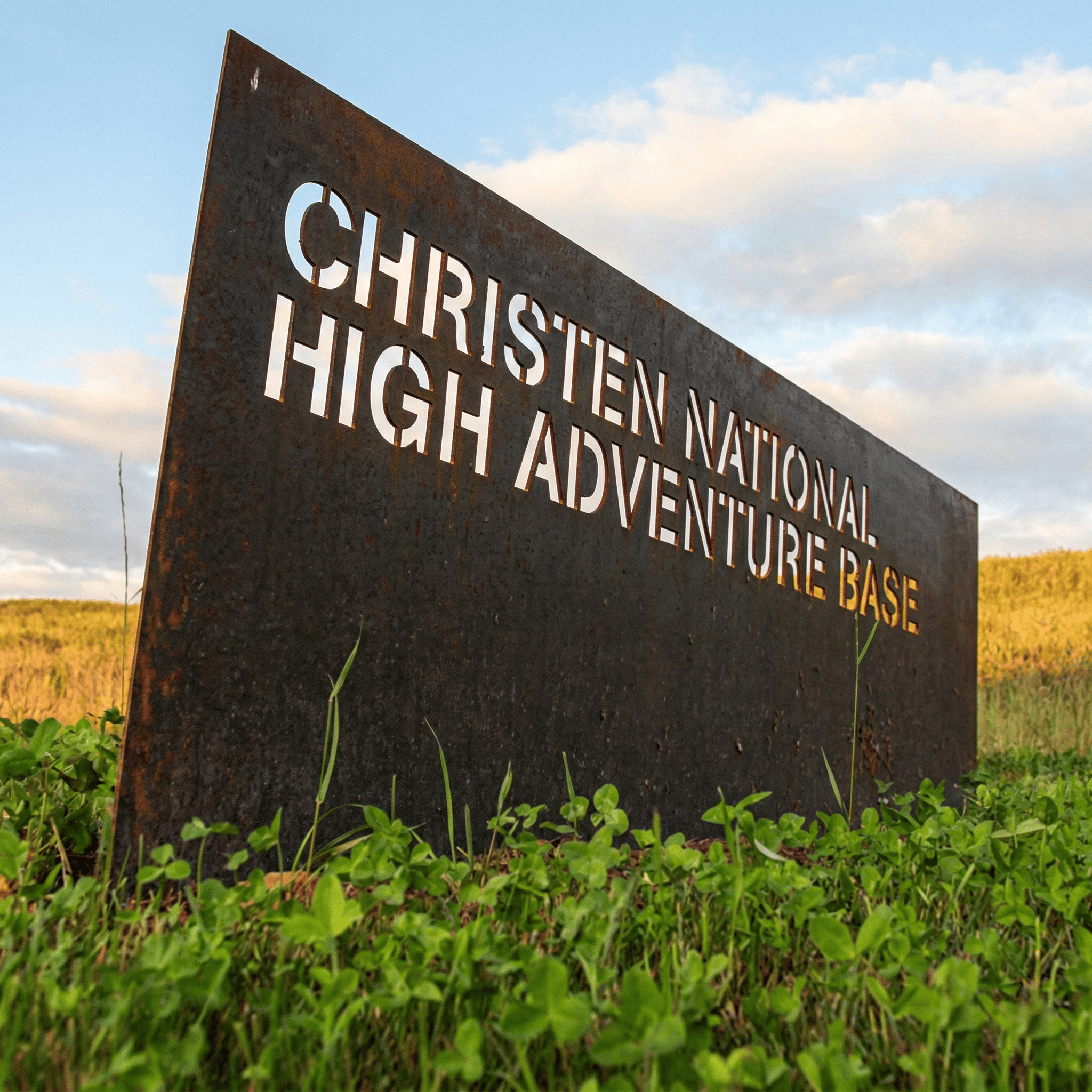 Weathered COR-TEN steel cut-out entry monument sign for Christen National High Adventure Base at Summit Bechtel Reserve, rugged outdoor placemaking signage design by RSM Design