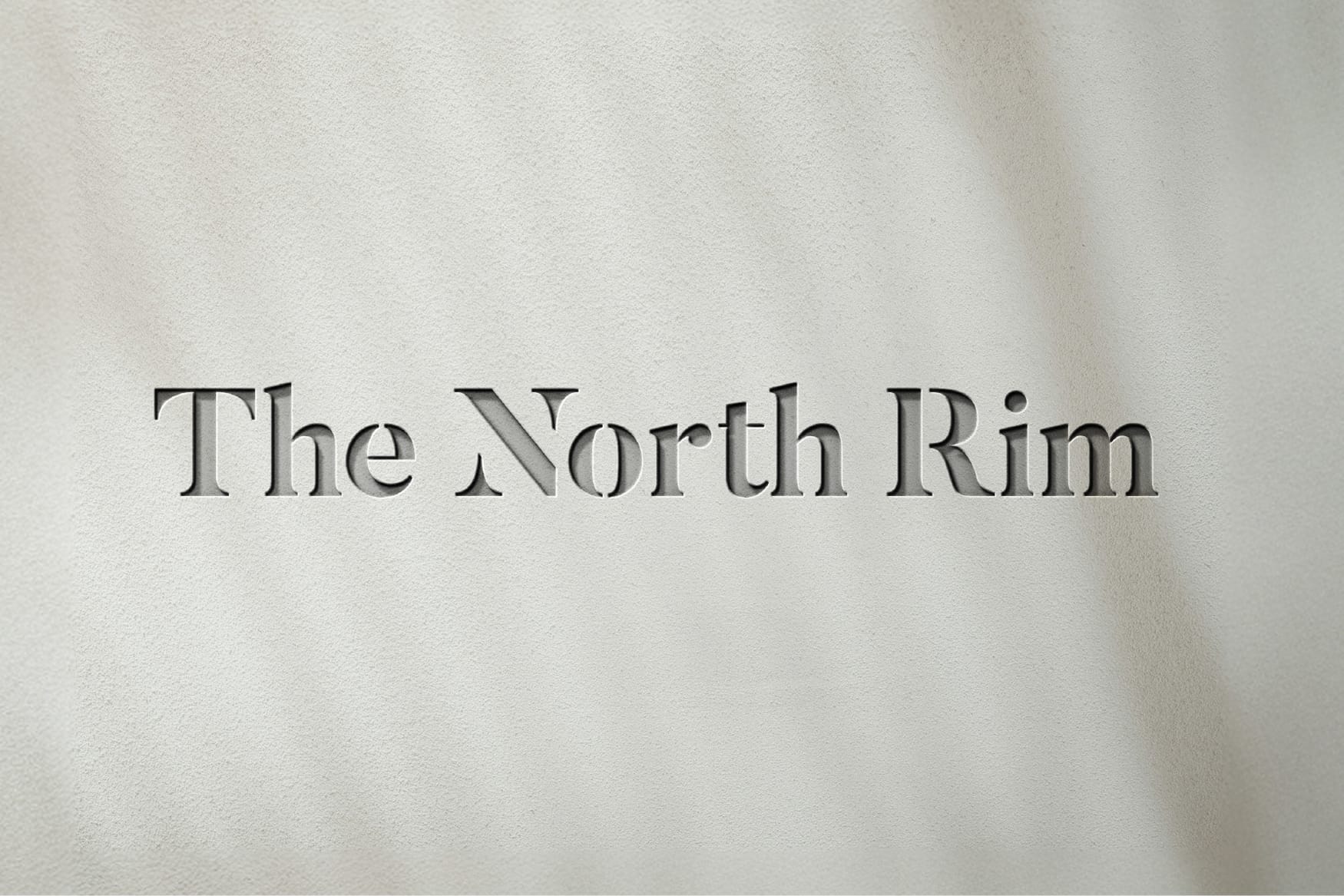 The North Rim serif wordmark logo etched into textured stucco wall, brand identity design by RSM Design