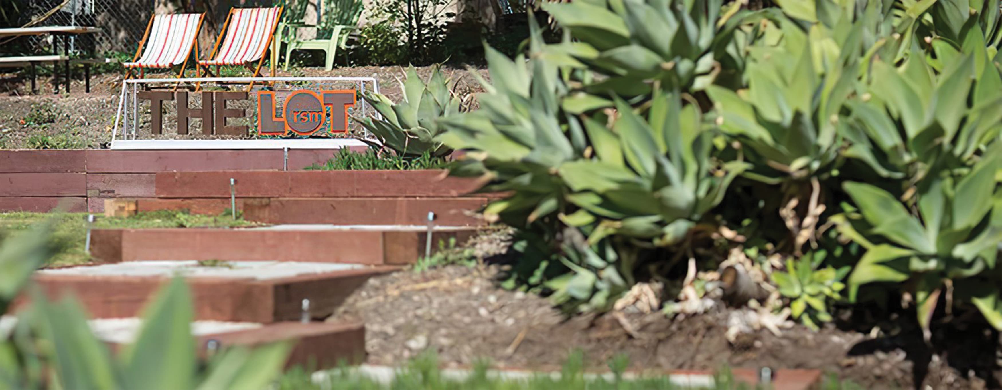 An outdoor space featuring a fabricated sign, seating, and succulent vegetation.