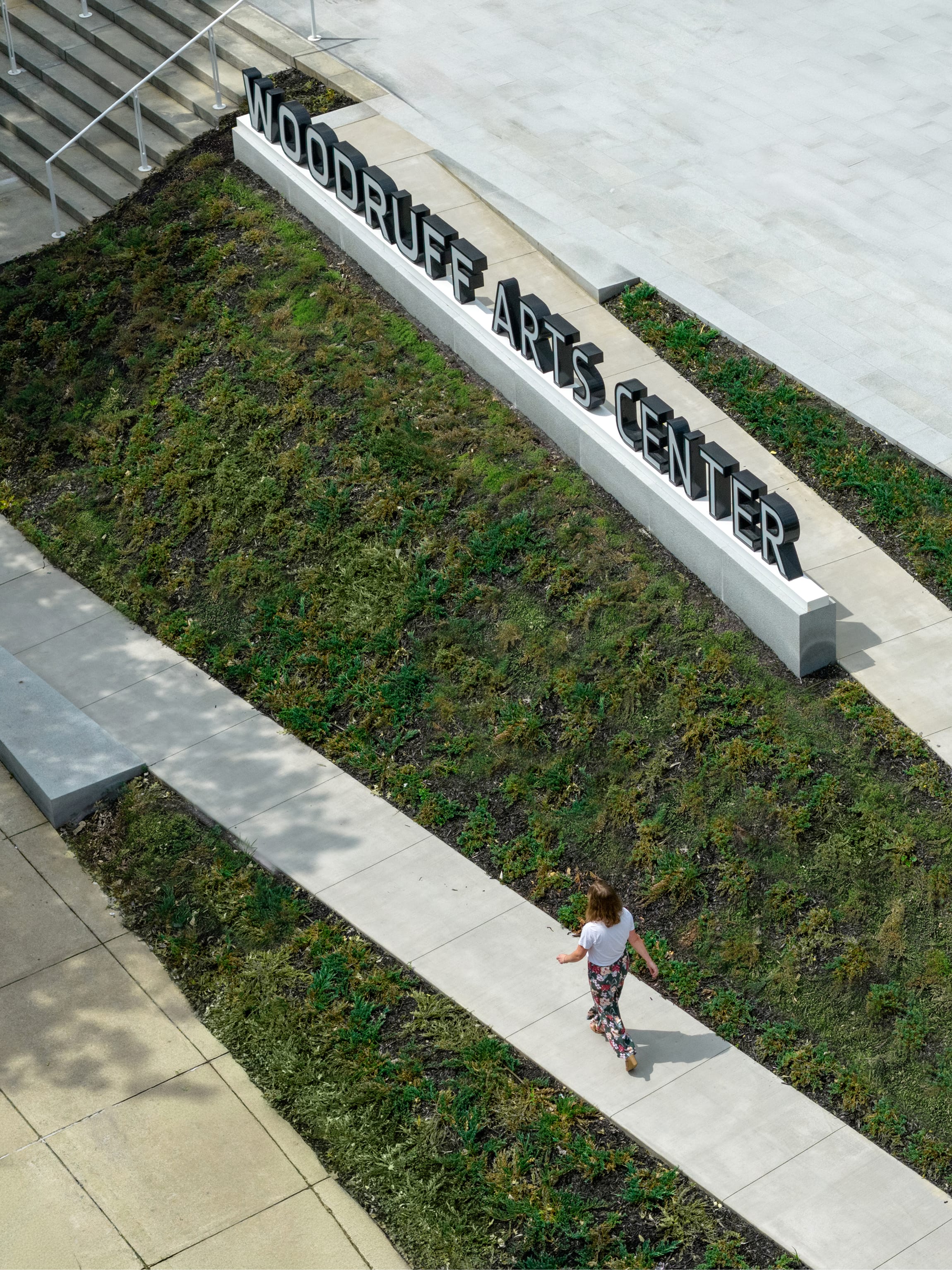 Aerial view of dimensional "WOODRUFF ARTS CENTER" letters set into a landscaped berm alongside a walking path in Midtown Atlanta – campus wayfinding and environmental graphic design by RSM Design.