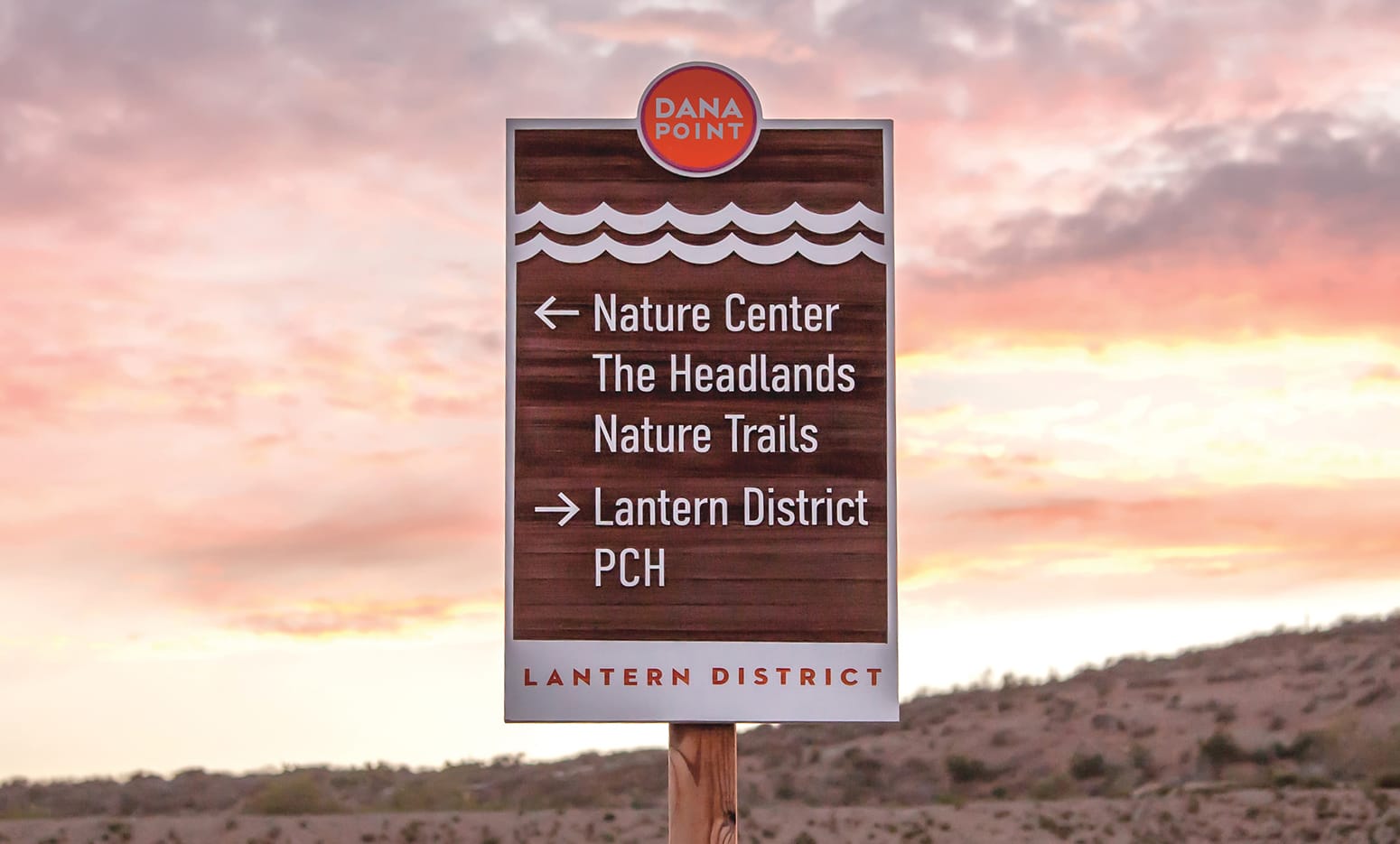 Wayfinding sign directing to the Nature Center, Headlands, and Lantern District, with the Dana Point logo and wave motif - environmental graphic design by RSM Design