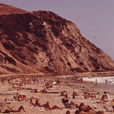 Vintage photograph of beachgoers along the sand at the base of a coastal bluff in Dana Point