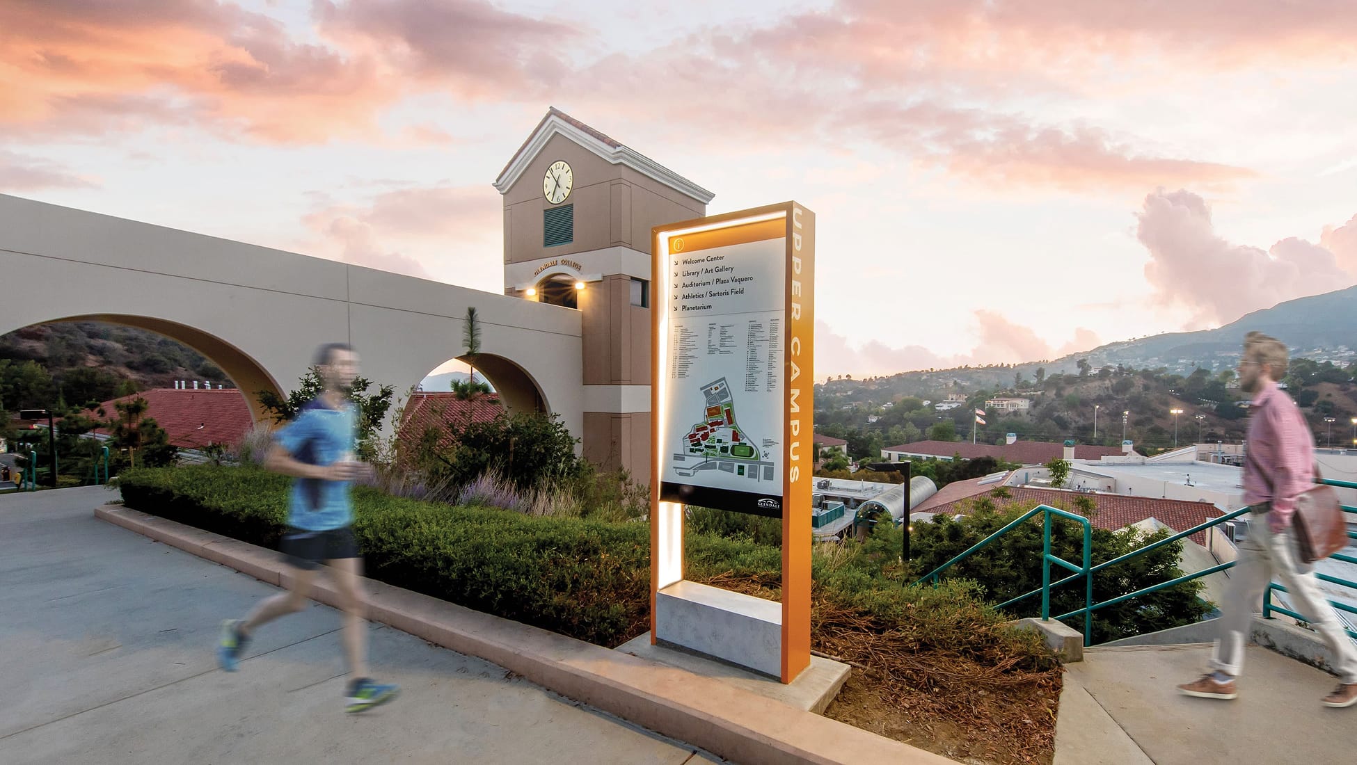 Wayfinding pylon sign at Glendale Community College upper campus entrance at dusk, designed by RSM Design, featuring illuminated orange frame and campus directory map