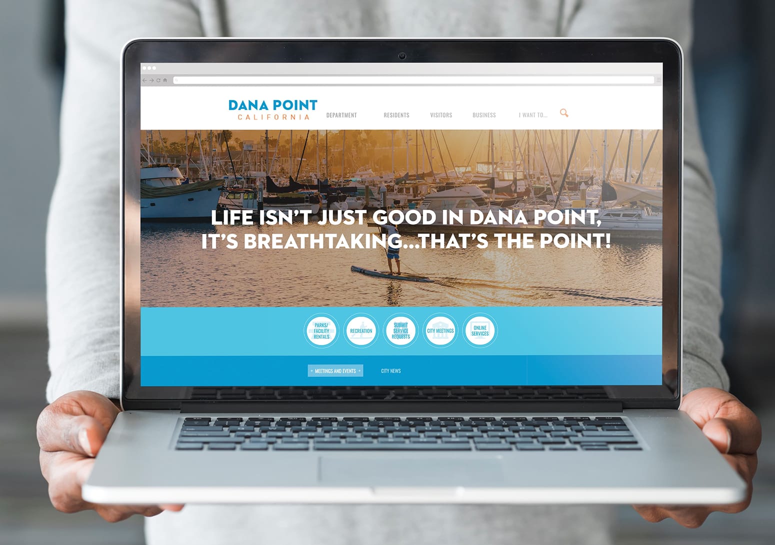 Laptop mockup of the City of Dana Point website homepage with harbor photography and paddleboarder - website design by RSM Design