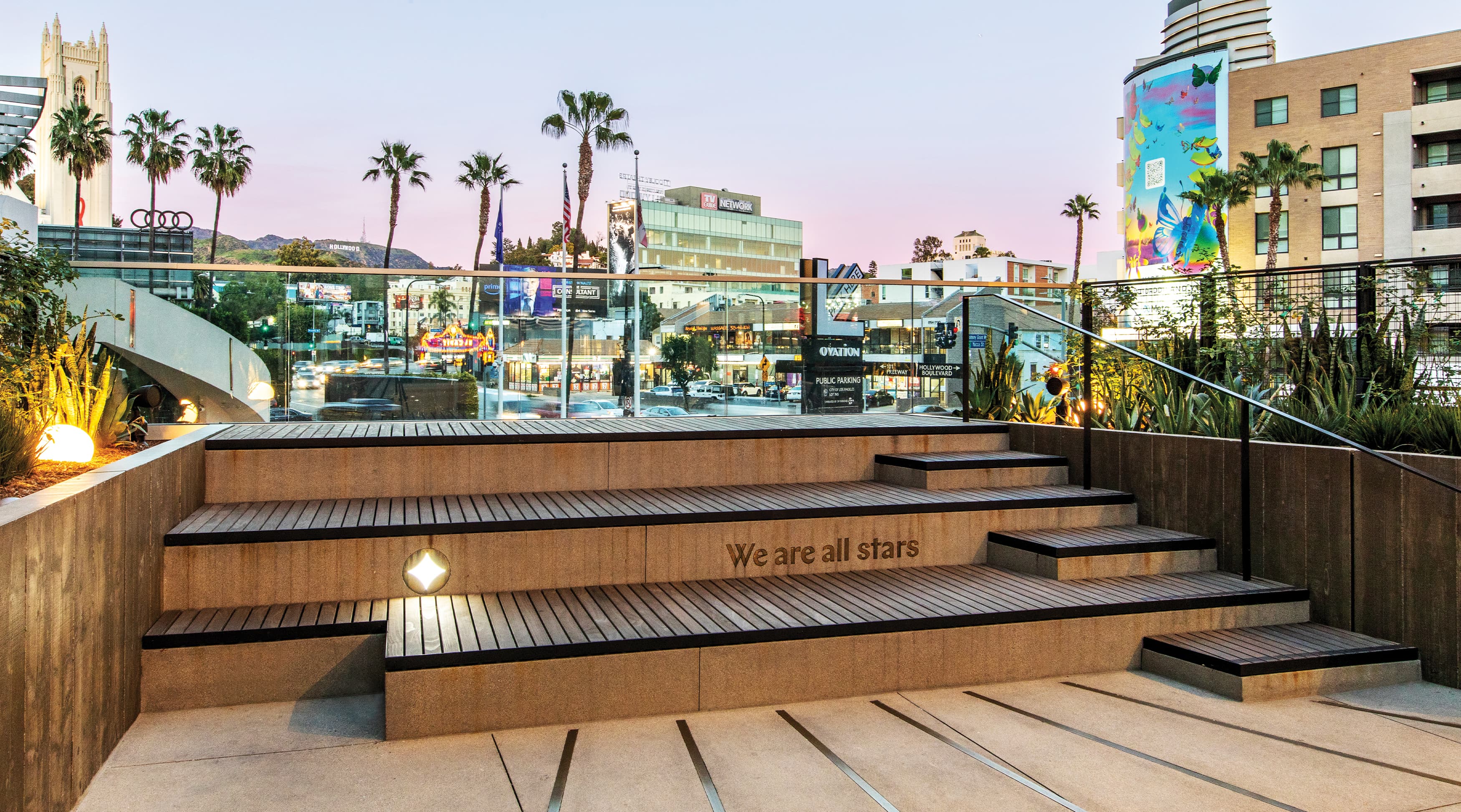"We are all stars" bronze letters inlayed on viewing deck steps with Hollywood sign in the background done by RSM Design for Ovation Hollywood in Los Angeles, California.